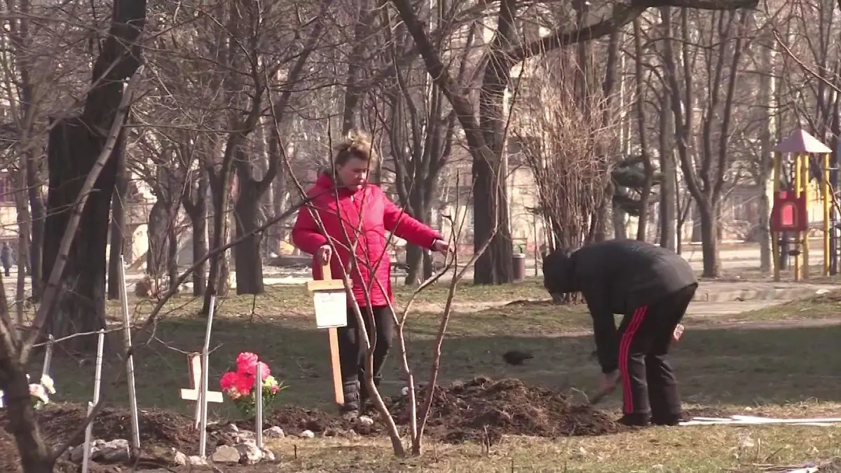 Ukrainische Frauen heben mit einer Schaufel Gräber in einem Park aus, um ihre Familienangehörigen zu begraben.