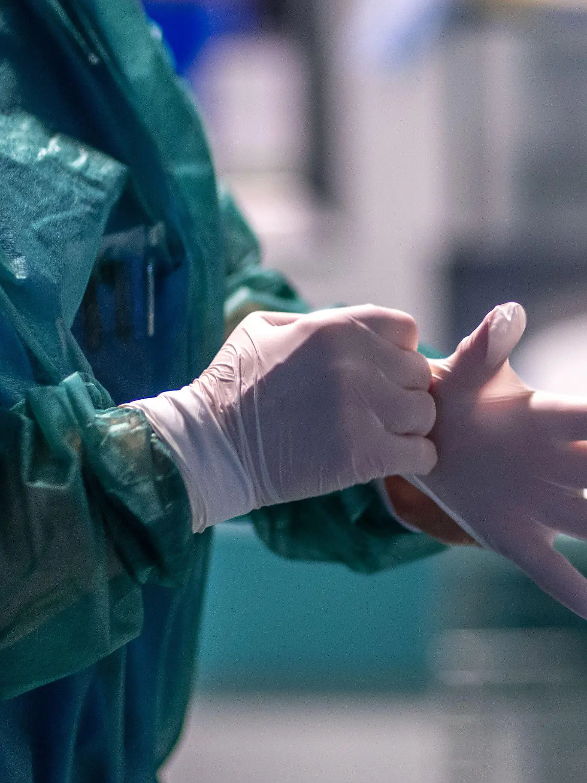 30.11.2021, Mecklenburg-Vorpommern, Rostock: Krankenpflegerin Anne-Marie Kalinowski legt vor einem der Behandlungszimmer der Intensivstation in der Universitätsmedizin Rostock ihre Schutzkleidung an. Angesichts der sprunghaft zunehmenden Zahl von Corona-Infizierten und der hohen Auslastung der Intensivstationen hat die Universitätsmedizin einen Covid-Ethikbeirat gebildet. Auch Patienten aus Sachsen werden in der Klinik behandelt. Foto: Jens Büttner/dpa-Zentralbild/dpa +++ dpa-Bildfunk +++