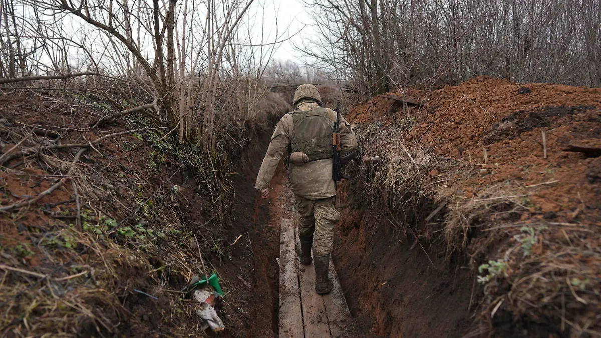 23.02.2022, Ukraine, Svitlodarsk: Ein ukrainischer Soldat geht durch einen Graben an der Trennlinie zwischen dem von der Ukraine und dem von pro-russischen Separatisten gehaltenen Gebiet in der Nähe von Svitlodarsk in der Ostukraine. Die Ukraine rüstet sich für einen Krieg mit Russland. Präsident Selenskyj kündigte eine Teilmobilmachung von Reservisten an. Foto: Evgeniy Maloletka/AP/dpa +++ dpa-Bildfunk +++