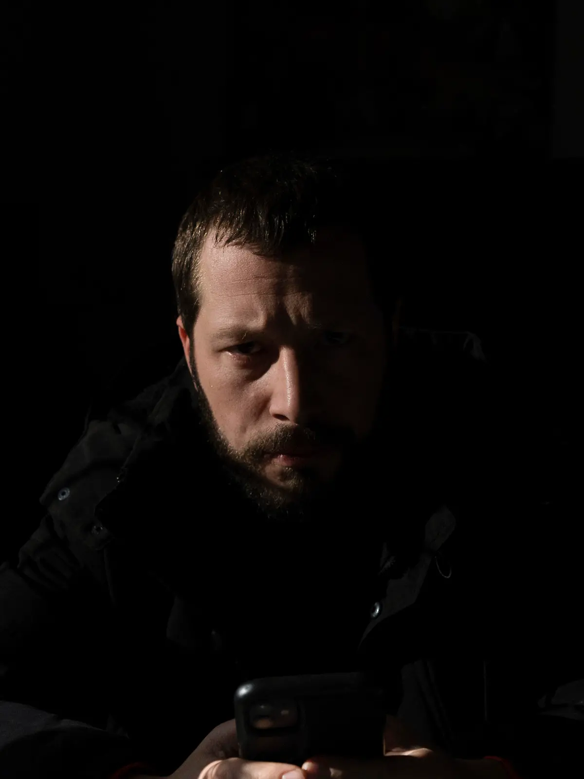 Associated Press videographer Mstyslav Chernov reads news on his phone three days before the start of Russian invasion in Volnovakha, Ukraine, Monday, Feb. 21, 2022. On the evening of Feb. 23, Chernov headed to Mariupol with colleague Evgeniy Maloletka. (AP Photo/Evgeniy Maloletka)