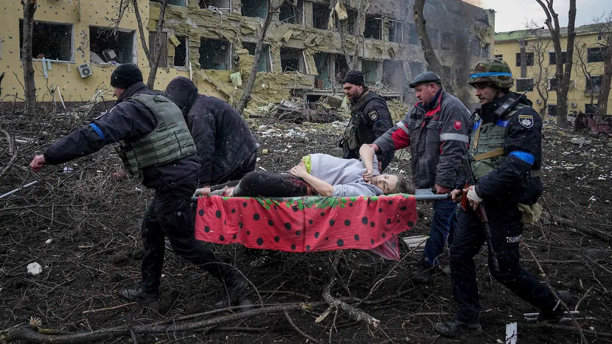 09.03.2022, Ukraine, Mariupol: Ukrainische Rettungskräfte und Freiwillige tragen eine verletzte schwangere Frau aus einer Entbindungsklinik, die durch Beschuss in Mariupol, Ukraine, beschädigt wurde. (zu dpa «Schwangere und ungeborenes Kind nach Angriff in Mariupol gestorben») Foto: Evgeniy Maloletka/AP/dpa +++ dpa-Bildfunk +++