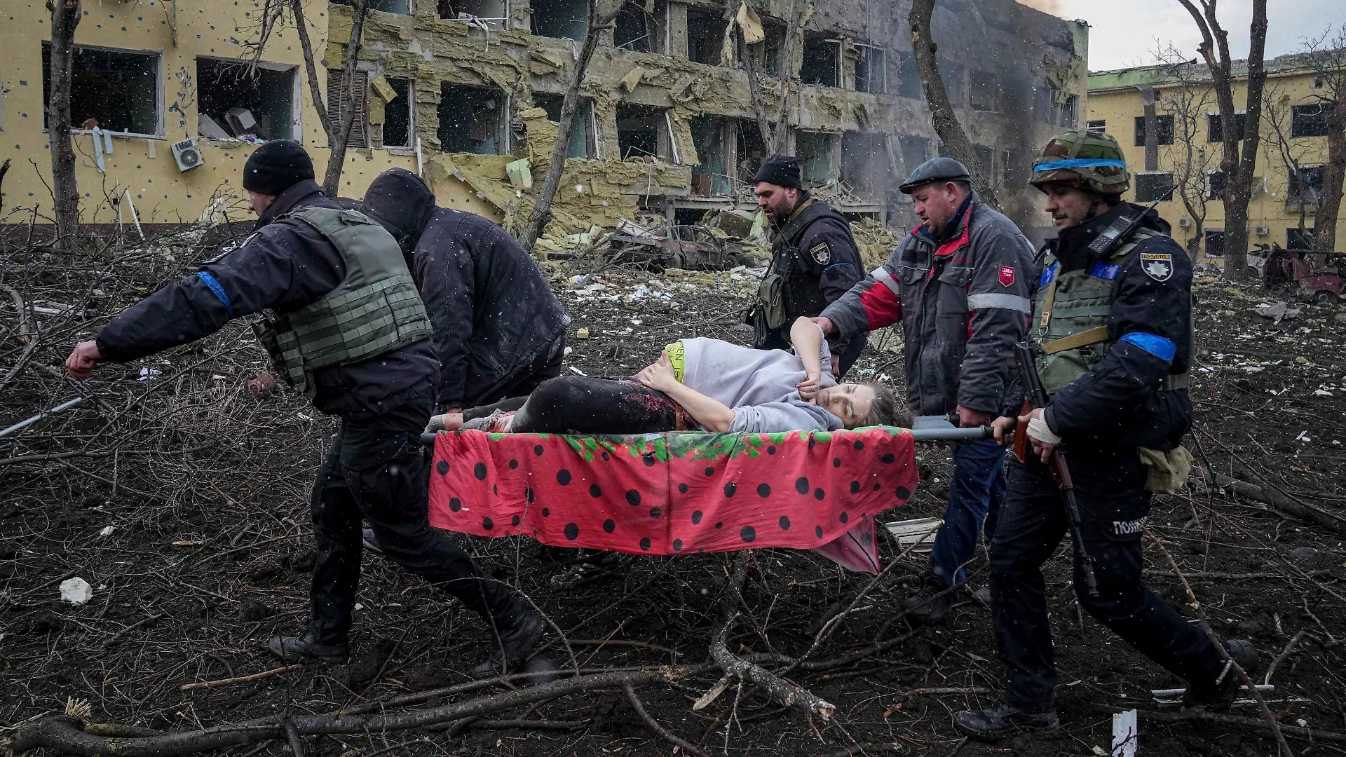 09.03.2022, Ukraine, Mariupol: Ukrainische Rettungskräfte und Freiwillige tragen eine verletzte schwangere Frau aus einer Entbindungsklinik, die durch Beschuss in Mariupol, Ukraine, beschädigt wurde. (zu dpa «Schwangere und ungeborenes Kind nach Angriff in Mariupol gestorben») Foto: Evgeniy Maloletka/AP/dpa +++ dpa-Bildfunk +++