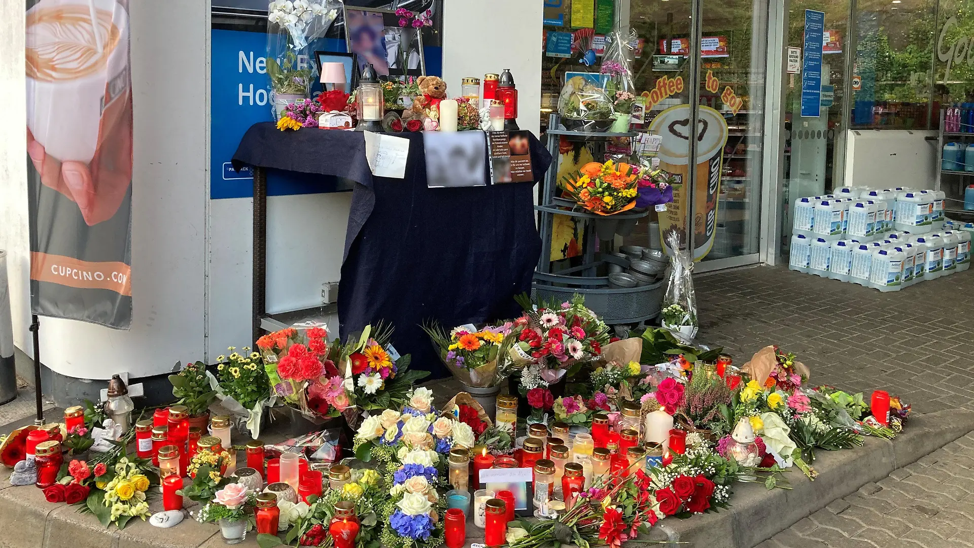 ARCHIV - 20.09.2021, Rheinland-Pfalz, Idar-Oberstein: Blumen und Kerzen sind vor einer Tankstelle aufgestellt. Ein junger Kassierer war am 18. September 2021 von einem mit einer Pistole bewaffneten Mann erschossen worden. (zu dpa «Prozess gegen mutmaßlichen Tankstellen-Mörder beginnt») Foto: Birgit Reichert/dpa - ACHTUNG: Die aufgestellten Fotos wurden aus rechtlichen Gründen gepixelt +++ dpa-Bildfunk +++