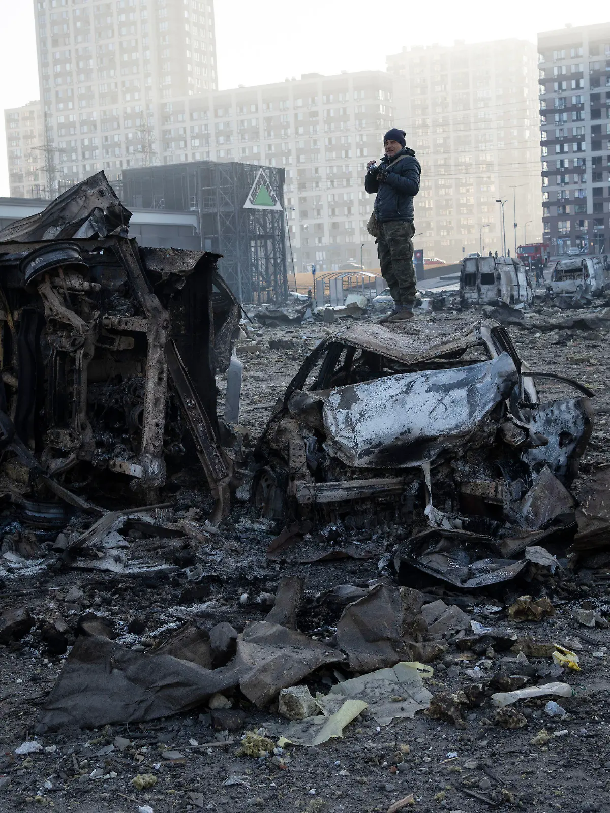 21.03.2022, Ukraine, Kiew: Ein Mann steht auf einem Autowrack  inmitten der Zerstörung, die nach dem Beschuss eines Einkaufszentrums in Kiew entstanden ist. Foto: Rodrigo Abd/AP/dpa +++ dpa-Bildfunk +++