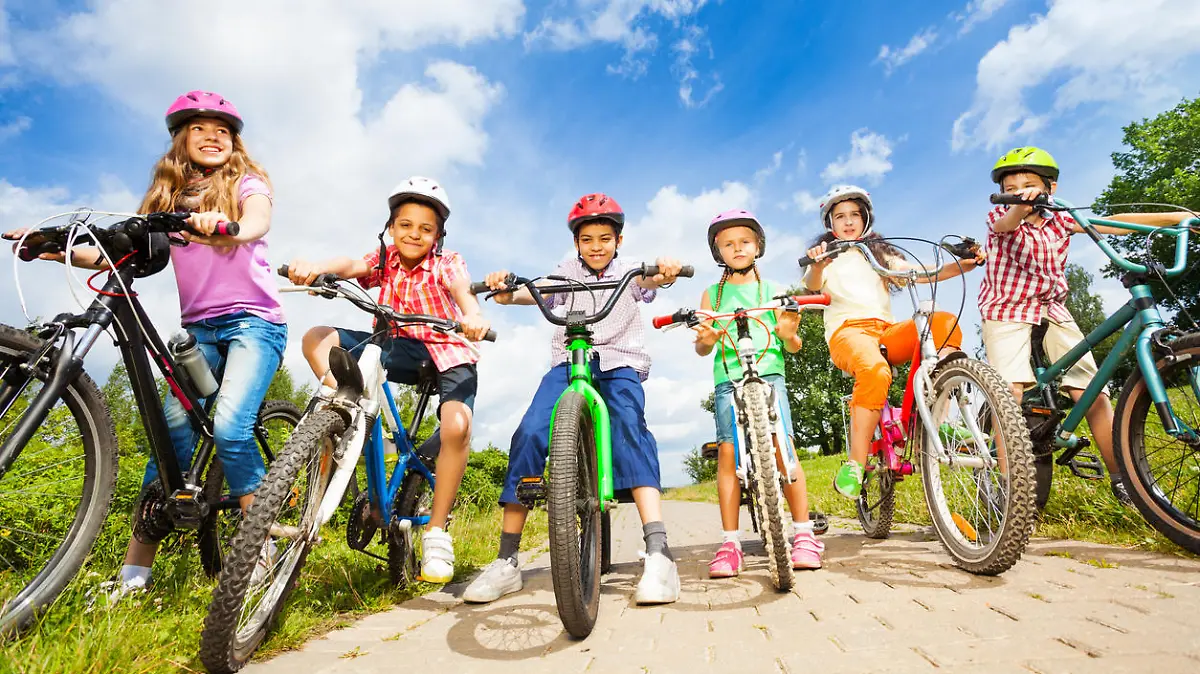 Below angle view of kids in helmets who hold their bikes and stand on path
