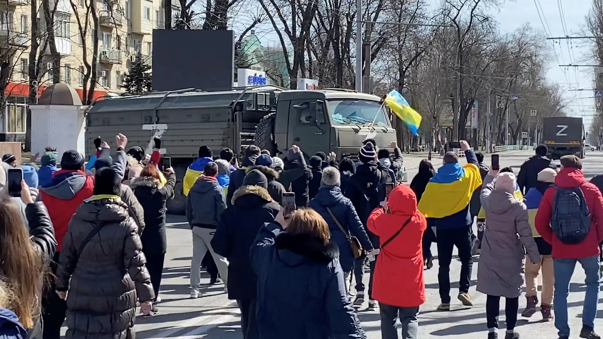 Demonstrators, some displaying Ukrainian flags, chant "go home" while walking towards retreating Russian military vehicles at a pro-Ukraine rally amid Russia's invasion, in Kherson, Ukraine March 20, 2022 in this still image from video obtained by REUTERS ATTENTION EDITORS - THIS IMAGE HAS BEEN SUPPLIED BY A THIRD PARTY. REUTERS HAS VERIFIED THE LOCATION