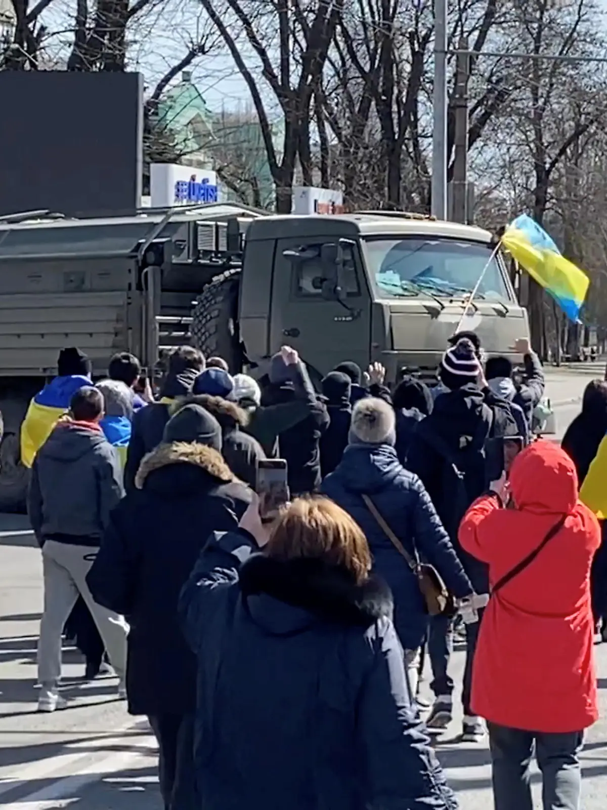Demonstrators, some displaying Ukrainian flags, chant "go home" while walking towards retreating Russian military vehicles at a pro-Ukraine rally amid Russia's invasion, in Kherson, Ukraine March 20, 2022 in this still image from video obtained by REUTERS  ATTENTION EDITORS - THIS IMAGE HAS BEEN SUPPLIED BY A THIRD PARTY. REUTERS HAS VERIFIED THE LOCATION