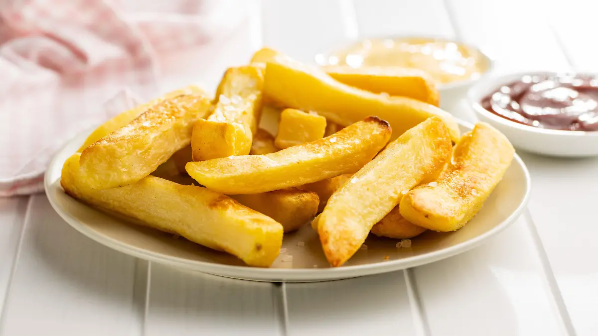 Big french fries. Fried potato chips on plate.