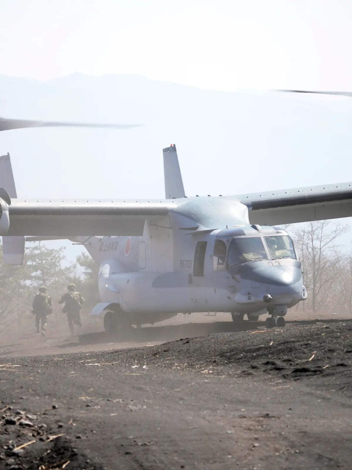 Members of the Japan Ground Self-Defense Force (JGSDF) rush out from a V-22 osprey as they take part in a joint military helicopter borne operation drill between Japan Ground Self-Defense Force (JGSDF) and U.S. Marines at the Higashi Fuji range in Gotemba, southwest of Tokyo, Tuesday, March 15, 2022. (AP Photo/Eugene Hoshiko)