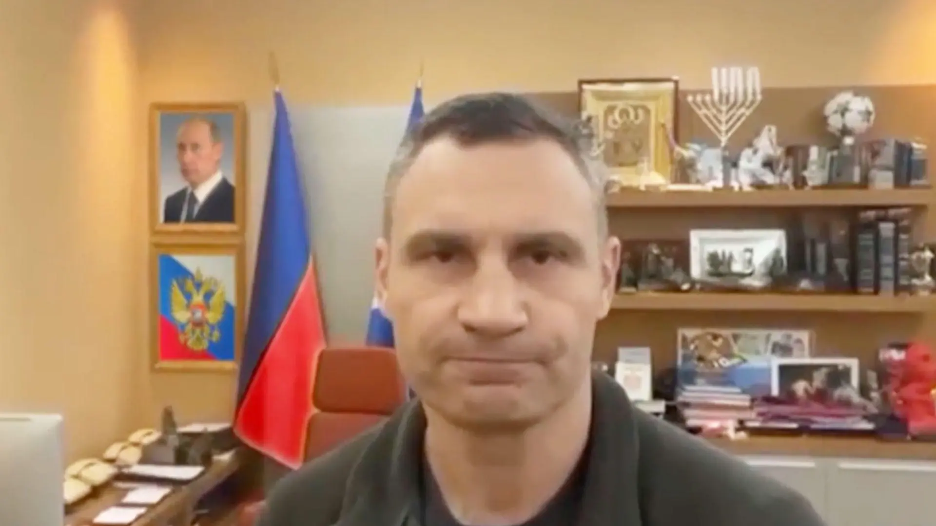 Screenshot aus einem Video, in dem Vitali Klitschko in seinem Büro vor einem Bild von Putin und der russischen Flagge steht.
