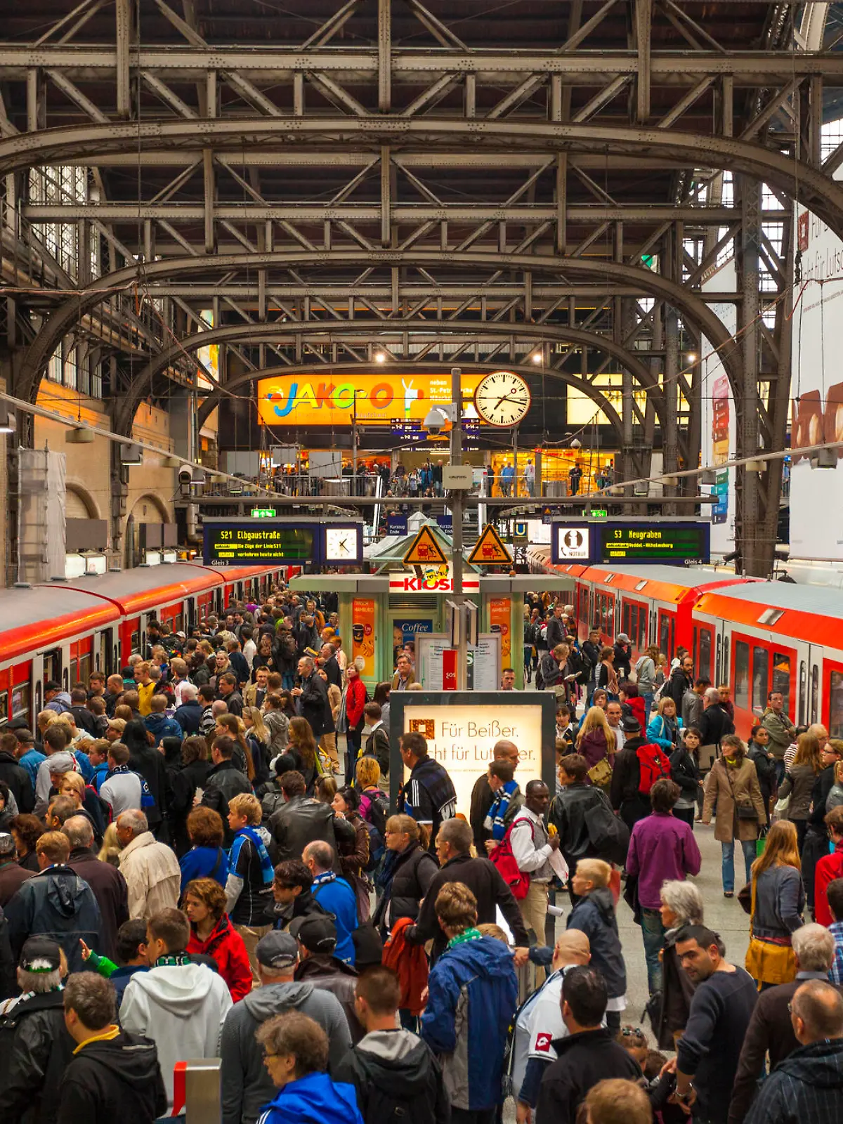 "Hamburg, Germany - September 17, 2011: Crowded station platform of the Hamburg S-Bahn at the Hamburg hauptbahnhof. Many people can be seen on the platform, some of which can be seen wearing scarves and blue jerseys to support a local football team."