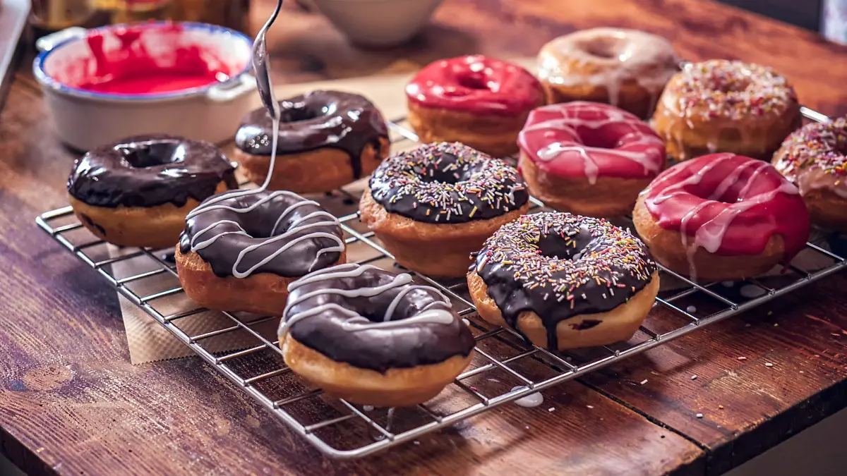 Preparing various homemade donuts with colored icing and chocolate.