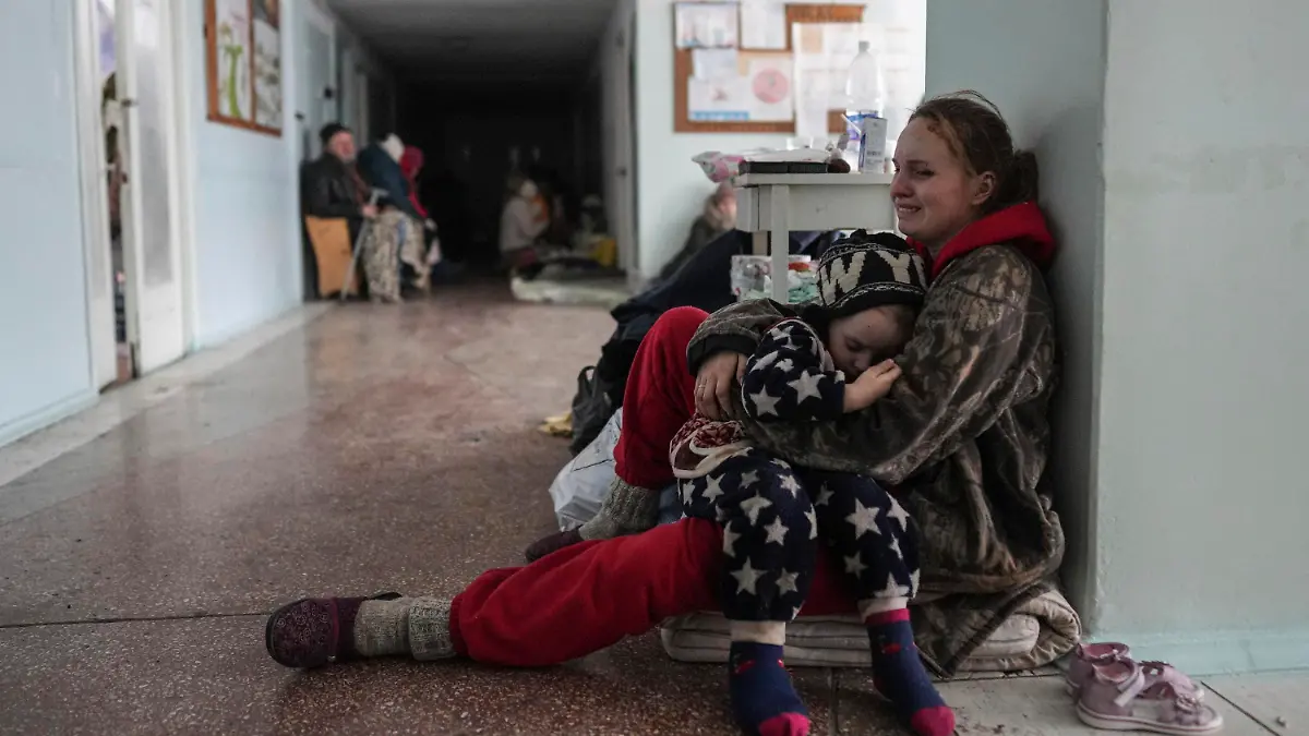 11.03.2022, Ukraine, Mariupol: Anastasia Erashova sitzt weinend auf dem Boden im Flur eines Krankenhauses in Mariupol, und umarmt eines ihrer Kinder. Zwei ihrer drei Kinder wurden während des Beschusses der Stadt getötet. Foto: Evgeniy Maloletka/AP/dpa +++ dpa-Bildfunk +++