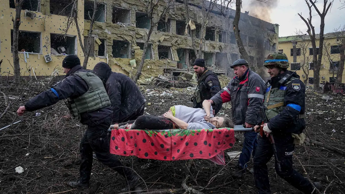 09.03.2022, Ukraine, Mariupol: Ukrainische Rettungskräfte und Freiwillige tragen eine verletzte schwangere Frau aus einer Entbindungsklinik, die durch Beschuss in Mariupol, Ukraine, beschädigt wurde. Foto: Evgeniy Maloletka/AP/dpa +++ dpa-Bildfunk +++