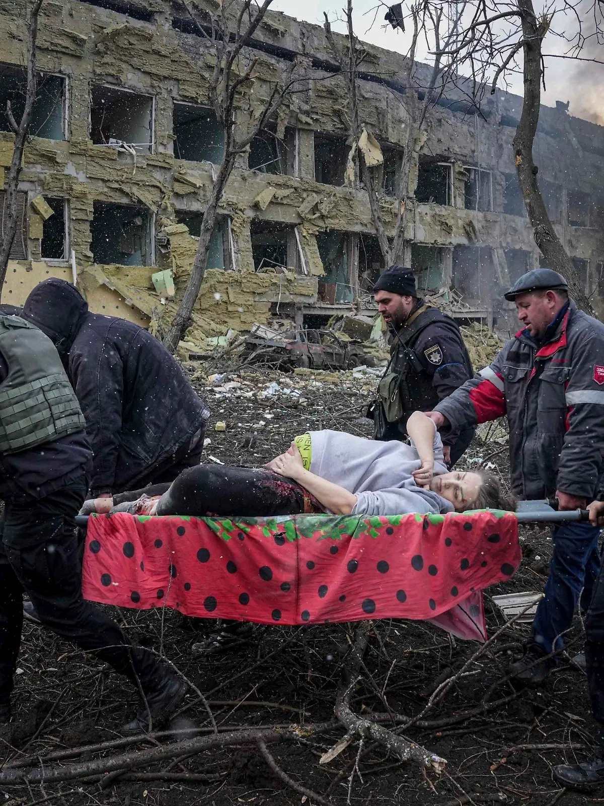 09.03.2022, Ukraine, Mariupol: Ukrainische Rettungskräfte und Freiwillige tragen eine verletzte schwangere Frau aus einer Entbindungsklinik, die durch Beschuss in Mariupol, Ukraine, beschädigt wurde. Foto: Evgeniy Maloletka/AP/dpa +++ dpa-Bildfunk +++