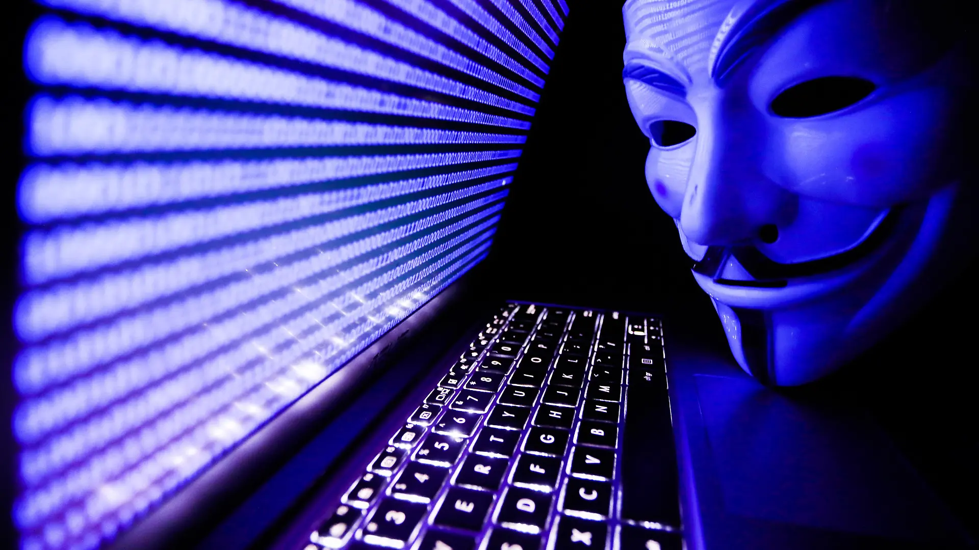 Binary code displayed on a laptop screen and Guy Fawkes mask are seen in this illustration photo taken in Krakow, Poland on March 1, 2022. Global hacker group Anonymous declared 'cyber war' against Russia. (Photo by Jakub Porzycki/NurPhoto)