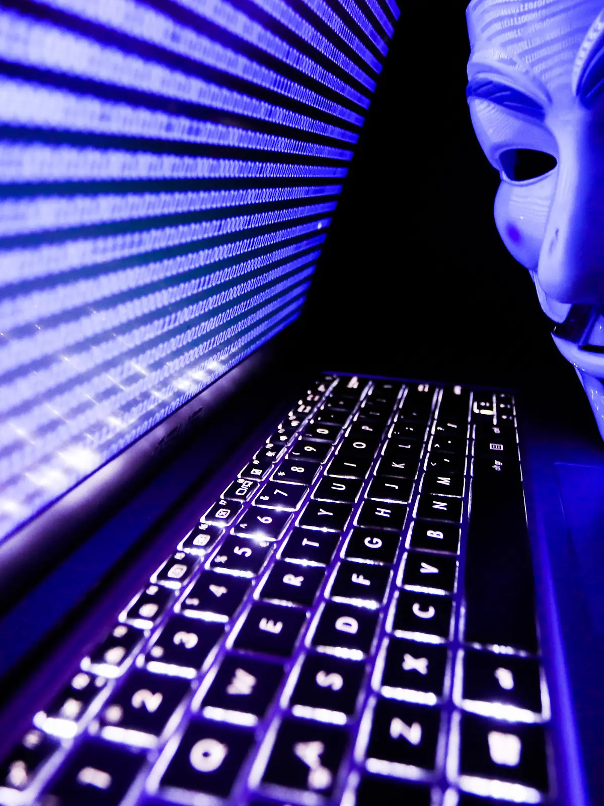 Binary code displayed on a laptop screen and Guy Fawkes mask are seen in this illustration photo taken in Krakow, Poland on March 1, 2022. Global hacker group Anonymous declared 'cyber war' against Russia. (Photo by Jakub Porzycki/NurPhoto)