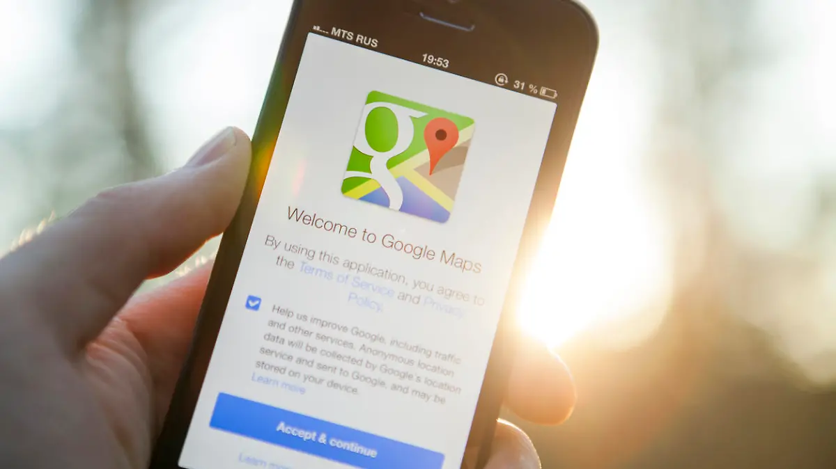Moscow, Russia - August 29, 2013: Man hand holding iPhone 5 with Google Maps app on a sunset background. iPhone is product Apple Inc. Google Maps is a web mapping service application and technology provided by Google.