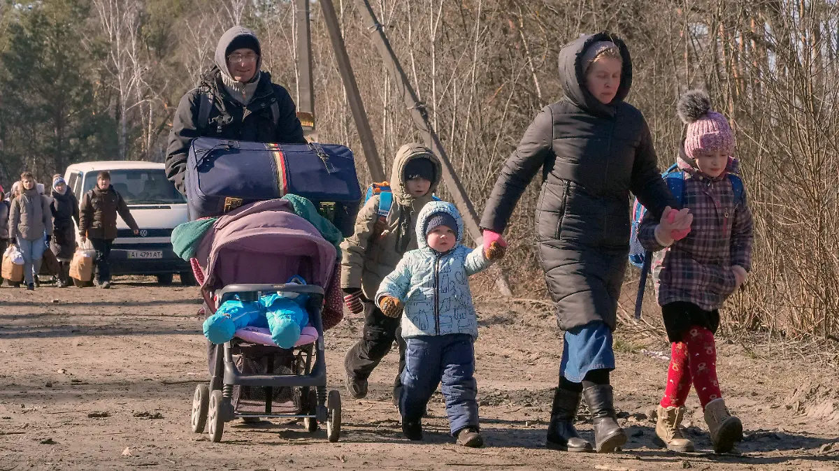 10.03.2022, Ukraine, Wyschgorod: Menschen tragen ihre Habseligkeiten, während sie eine Straße in einem Wald in der Region Wyschgorod in der Nähe von Kiew entlanggehen. Russlands zweiwöchiger Krieg in der Ukraine hat Tausende von Menschen getötet und mehr als 2 Millionen Menschen zur Flucht gezwungen und damit die Grundlagen der europäischen Sicherheit erschüttert. Foto: Efrem Lukatsky/AP/dpa +++ dpa-Bildfunk +++