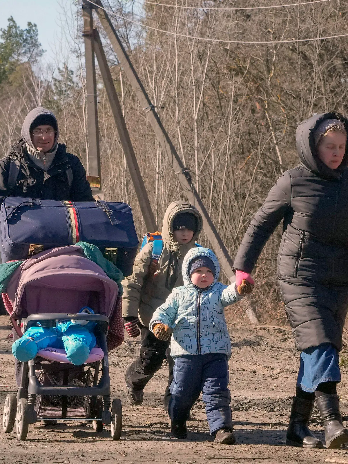 10.03.2022, Ukraine, Wyschgorod: Menschen tragen ihre Habseligkeiten, während sie eine Straße in einem Wald in der Region Wyschgorod in der Nähe von Kiew entlanggehen. Russlands zweiwöchiger Krieg in der Ukraine hat Tausende von Menschen getötet und mehr als 2 Millionen Menschen zur Flucht gezwungen und damit die Grundlagen der europäischen Sicherheit erschüttert. Foto: Efrem Lukatsky/AP/dpa +++ dpa-Bildfunk +++