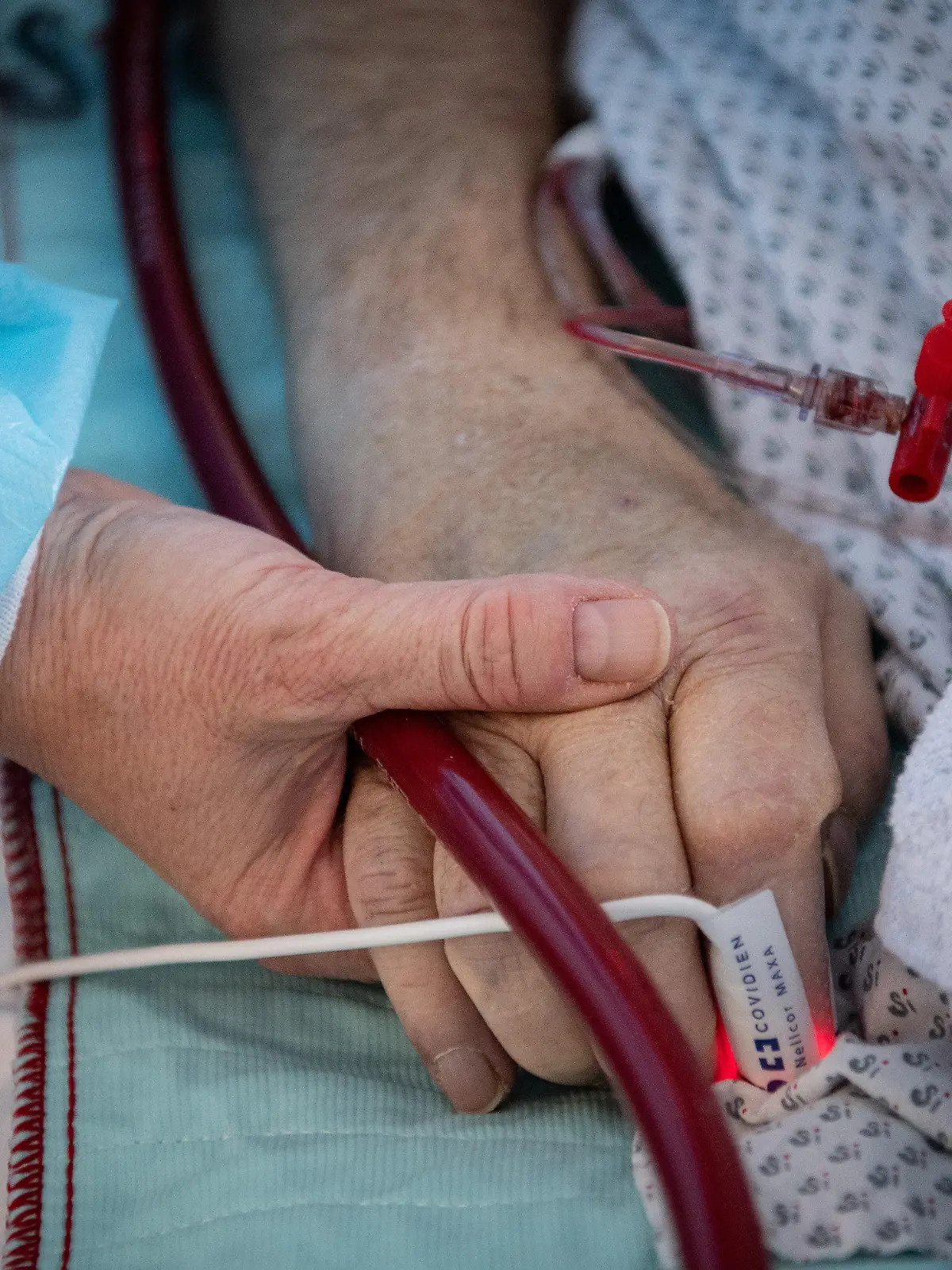 PRODUKTION - 16.02.2022, Hessen, Fulda: Eine Krankenschwester versorgt einen schwer an Corona erkrankten Patienten auf der Intensivstation des Klinikums in Fulda und hält dabei die Hand des Mannes. Viele Patienten mit schweren Verläufen liegen mehrere Wochen auf der Intensivstation, rund die Hälfte der künstlich beatmeten Patienten stirbt. (zu dpa "Sorgen um Engpässe in Kliniken und Altenheimen wegen Impfpflicht") Foto: Boris Roessler/dpa +++ dpa-Bildfunk +++