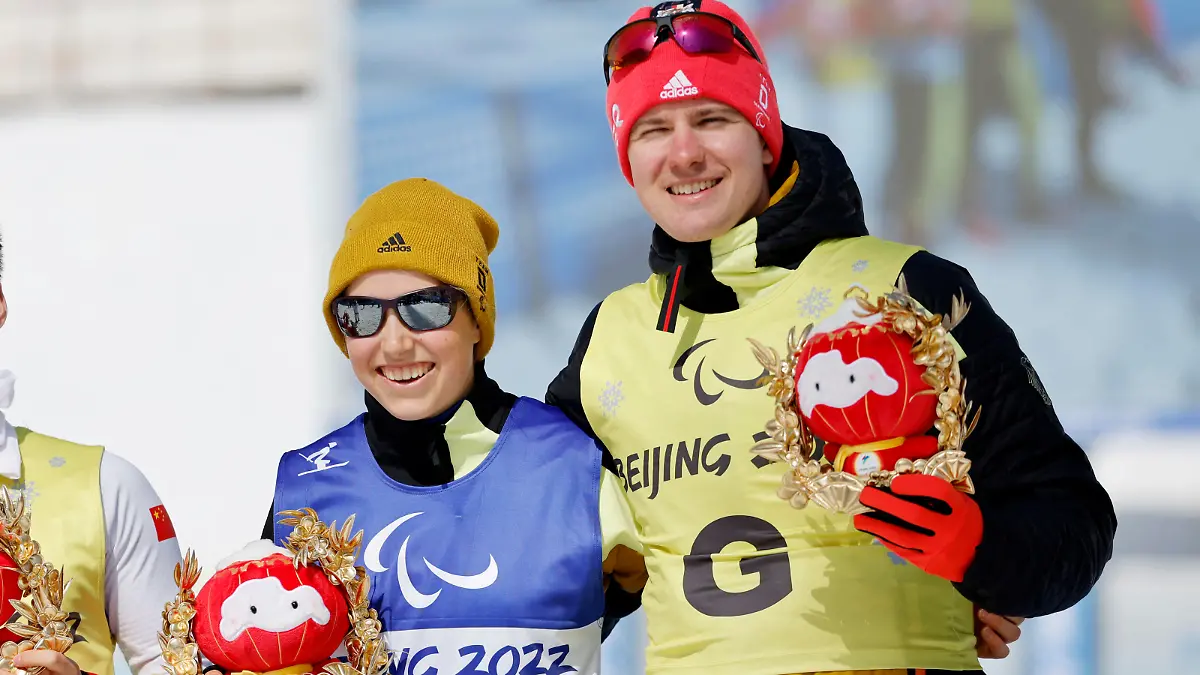 Beijing 2022 Winter Paralympic Games - Para Cross-Country Skiing - Women's Middle Distance Free Technique Vision Impaired - National Biathlon Centre, Zhangjiakou, China - March 12, 2022. Gold medallist Linn Kazmaier of Germany with guide Florian Baumann of Germany hold awards depicting Shuey Rhon Rhon, the mascot of the Beijing 2022 Winter Paralympic Olympics, during the flower ceremony. REUTERS/Issei Kato