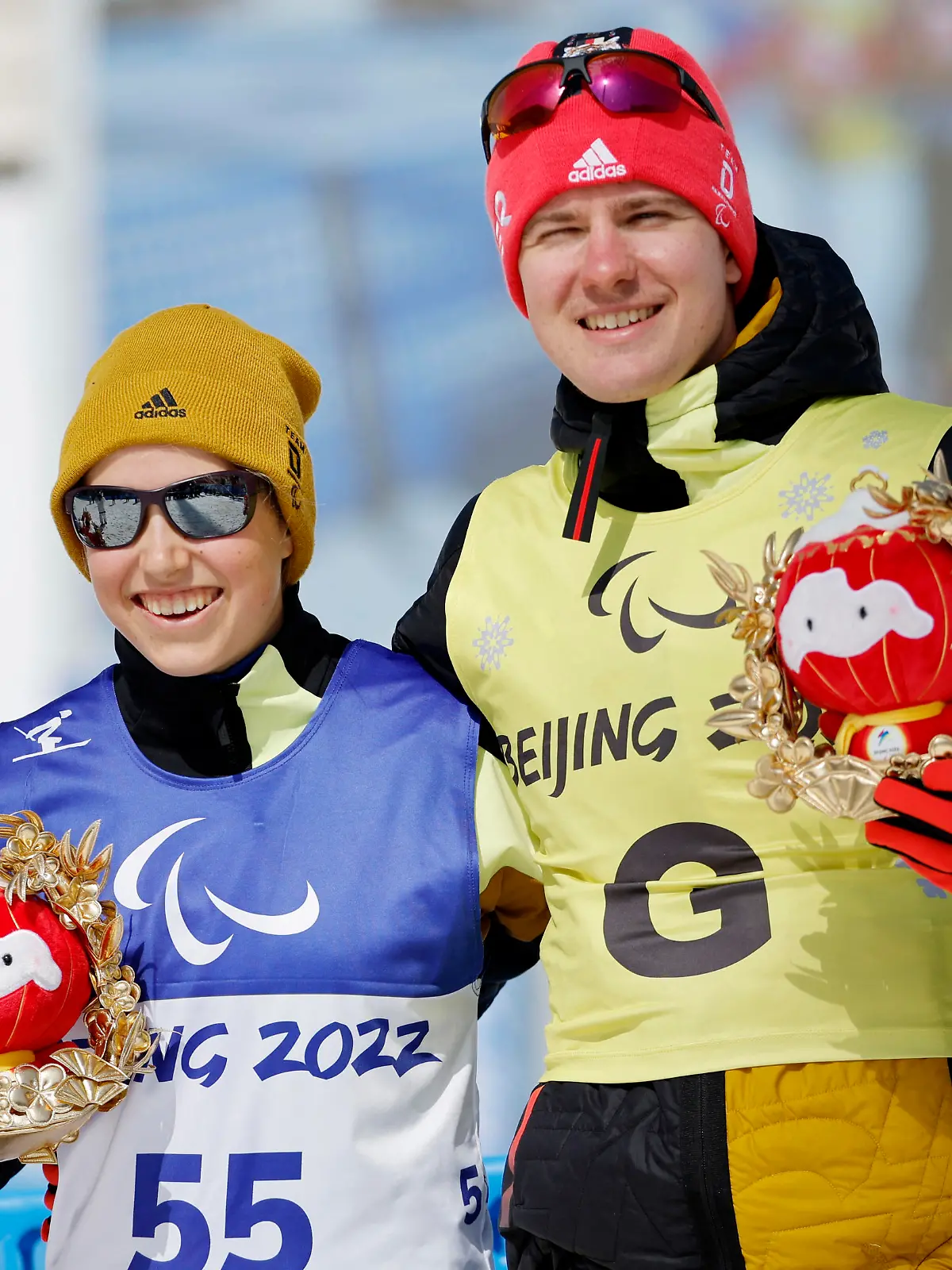 Beijing 2022 Winter Paralympic Games - Para Cross-Country Skiing - Women's Middle Distance Free Technique Vision Impaired - National Biathlon Centre, Zhangjiakou, China - March 12, 2022. Gold medallist Linn Kazmaier of Germany with guide Florian Baumann of Germany hold awards depicting Shuey Rhon Rhon, the mascot of the Beijing 2022 Winter Paralympic Olympics, during the flower ceremony. REUTERS/Issei Kato