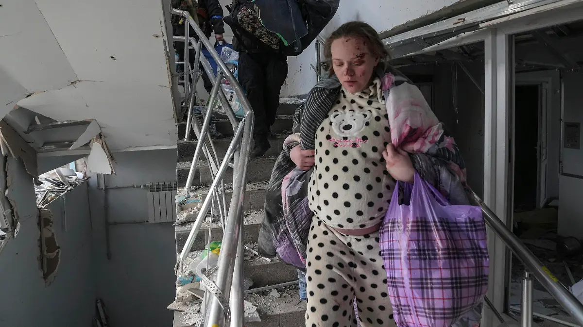 An injured pregnant woman walks downstairs in the damaged by shelling maternity hospital in Mariupol, Ukraine, Wednesday, March 9, 2022. A Russian attack has severely damaged a maternity hospital in the besieged port city of Mariupol, Ukrainian officials say. (AP Photo/Evgeniy Maloletka)