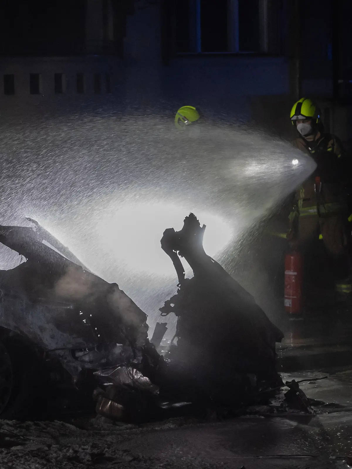 03.02.2021, Berlin: Einsatzkräfte der Feuerwehr löschen am Treptower Park ein Autowrack. Bei einem schweren Autounfall in Berlin-Treptow ist ein Mensch ums Leben gekommen, drei weitere wurden schwer verletzt. Foto: Paul Zinken/dpa +++ dpa-Bildfunk +++