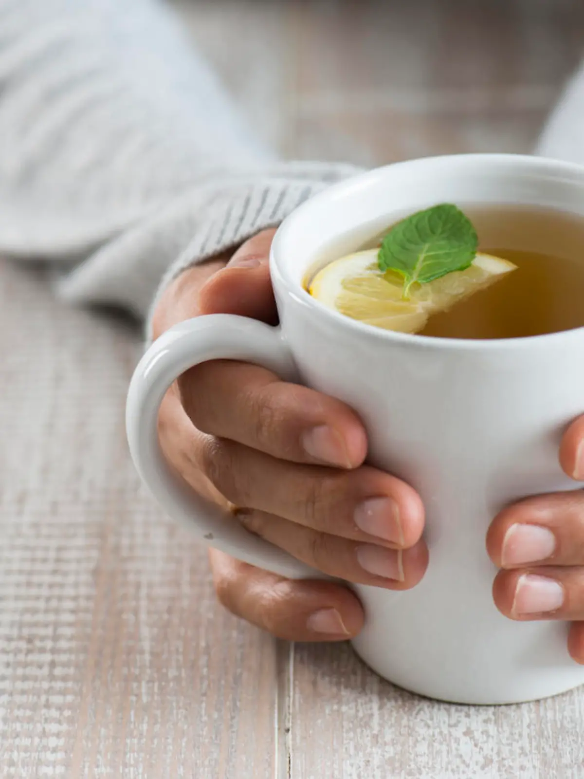Herbal tea on wood background. Woman holding mug.