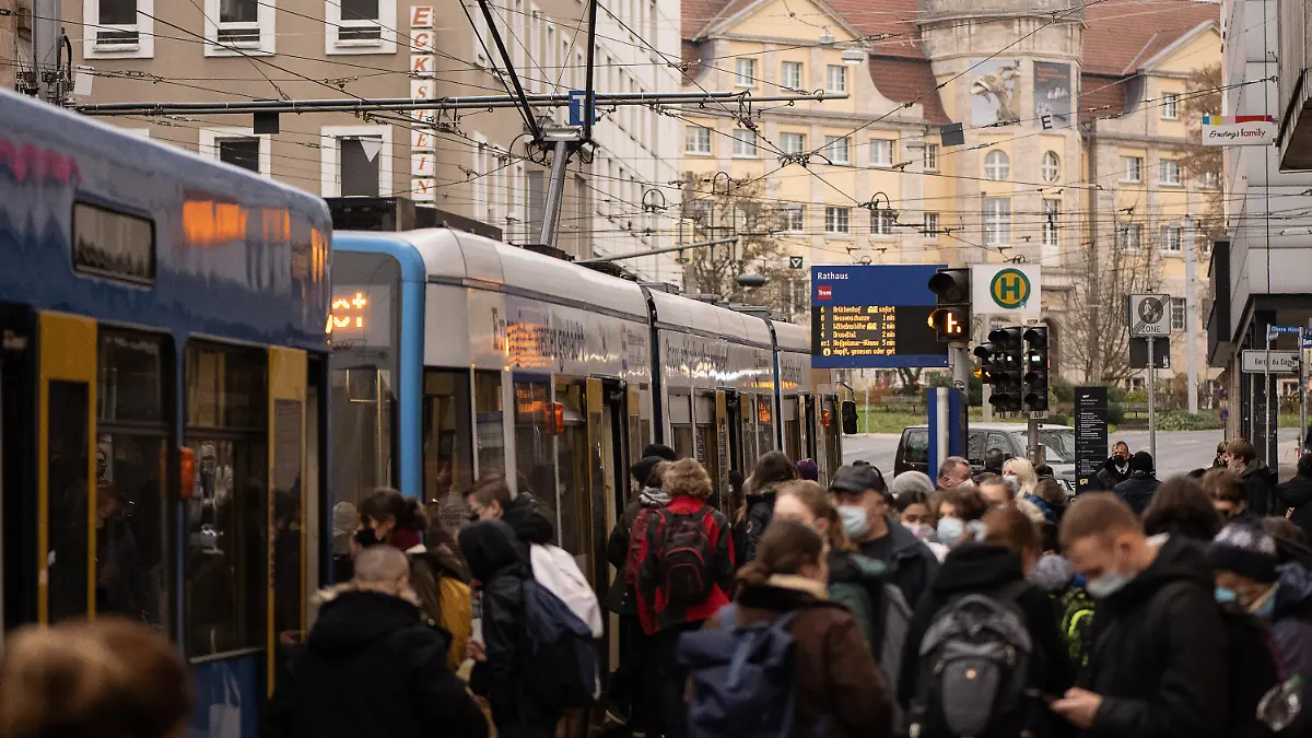 ARCHIV - 25.11.2021, Hessen, Kassel: Fahrgäste stehen an einer Haltestelle vor einer Straßenbahn der Kasseler Verkehrs-Gesellschaft (KVG). Wissenschaftleer erforschen derzeit, wie der öffentliche Nahverkehr pandemie-resistent gemacht werden kann (zu dpa-Text «Sicher in Bus und Bahn trotz Pandemie: Forschungsprojekt in Kassel») Foto: Swen Pförtner/dpa +++ dpa-Bildfunk +++