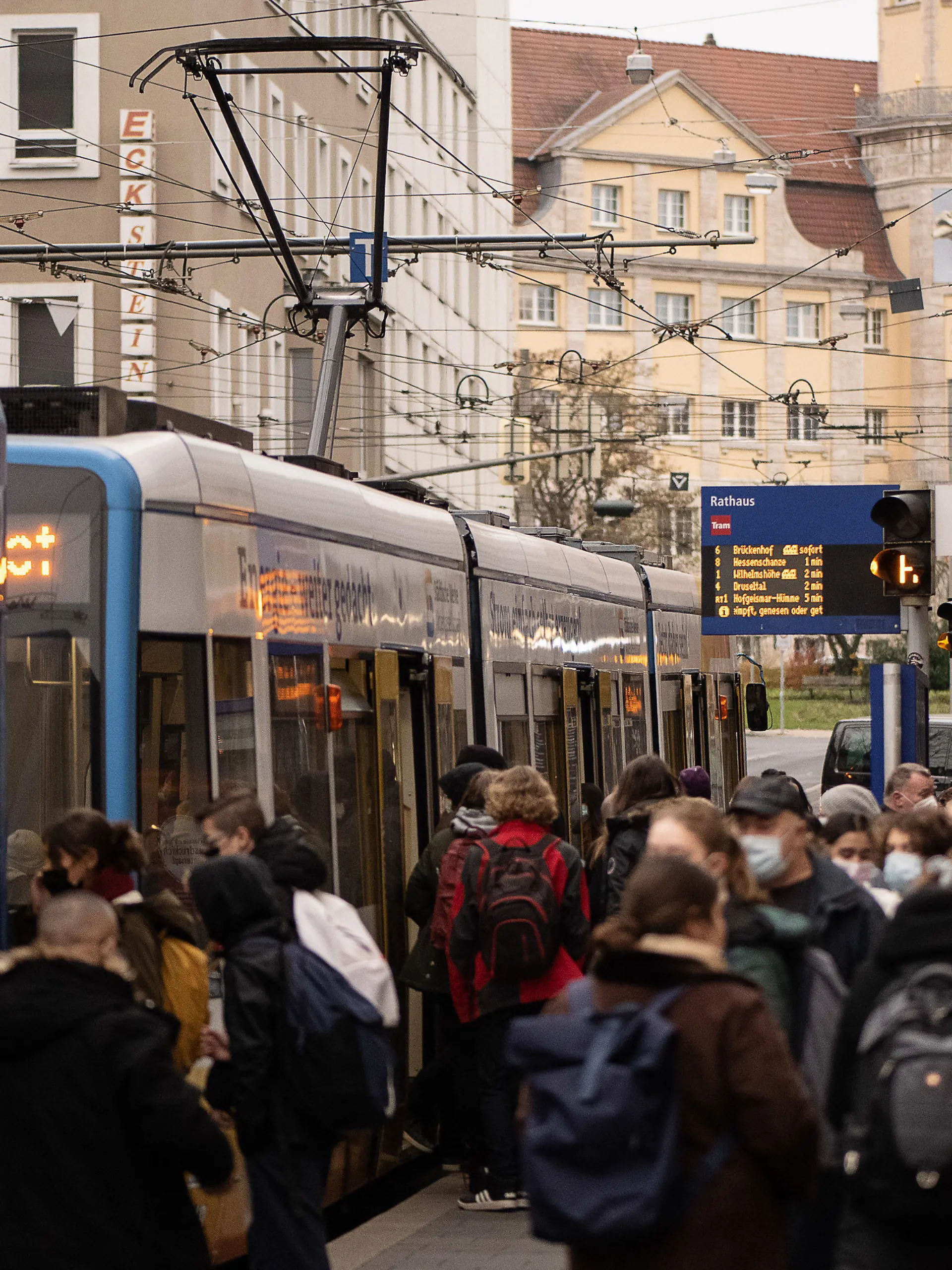 ARCHIV - 25.11.2021, Hessen, Kassel: Fahrgäste stehen an einer Haltestelle vor einer Straßenbahn der Kasseler Verkehrs-Gesellschaft (KVG). Wissenschaftleer erforschen derzeit, wie der öffentliche Nahverkehr pandemie-resistent gemacht werden kann (zu dpa-Text «Sicher in Bus und Bahn trotz Pandemie: Forschungsprojekt in Kassel») Foto: Swen Pförtner/dpa +++ dpa-Bildfunk +++