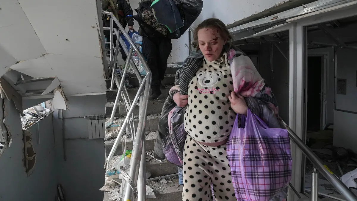 09.03.2022, Ukraine, Mariupol: Eine verletzte schwangere Frau geht die Treppe eines Entbindungskrankenhauses hinunter, das durch Beschuss in Mariupol, Ukraine, beschädigt wurde. Foto: Evgeniy Maloletka/AP/dpa +++ dpa-Bildfunk +++