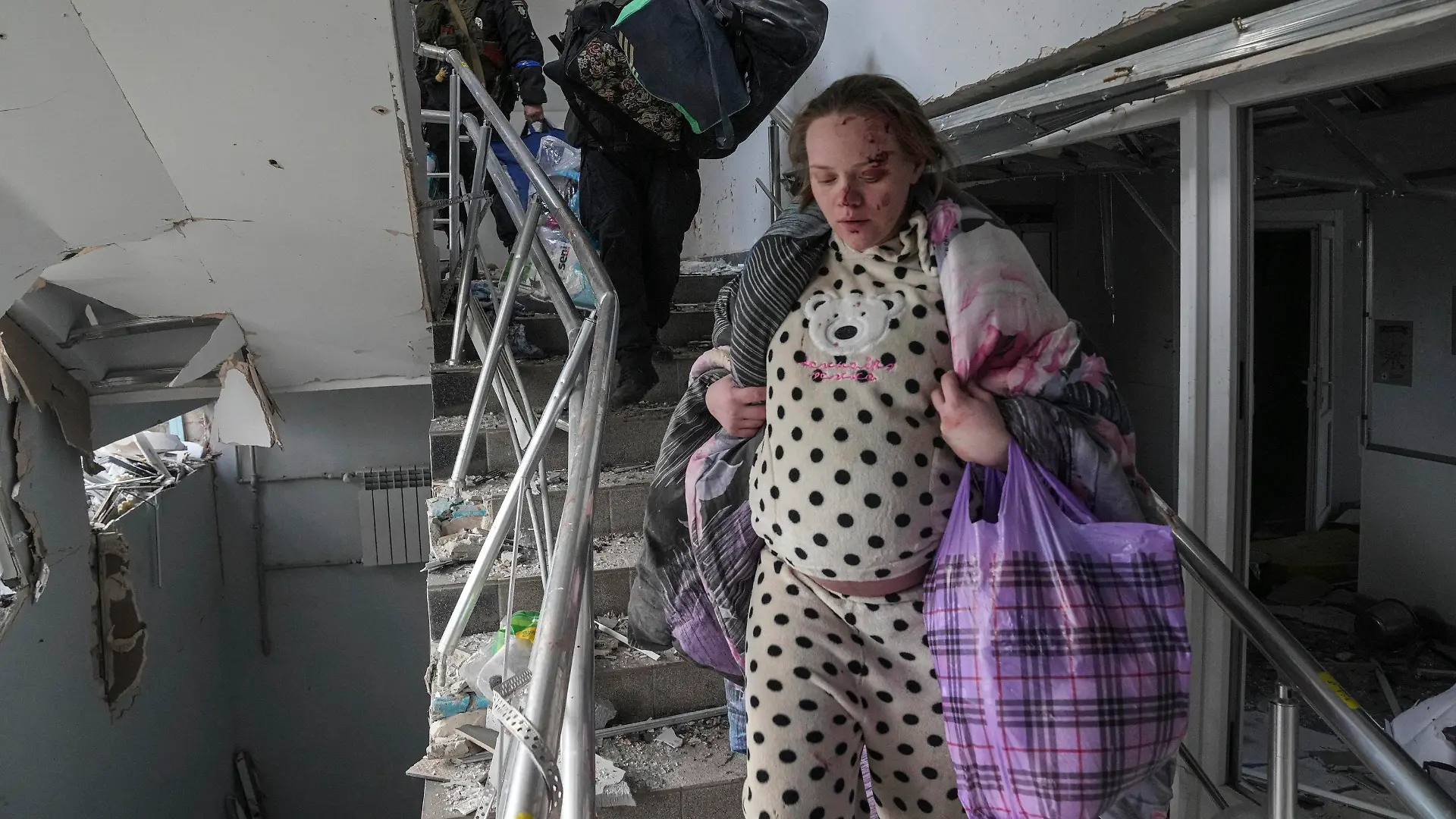 09.03.2022, Ukraine, Mariupol: Eine verletzte schwangere Frau geht die Treppe eines Entbindungskrankenhauses hinunter, das durch Beschuss in Mariupol, Ukraine, beschädigt wurde. Foto: Evgeniy Maloletka/AP/dpa +++ dpa-Bildfunk +++