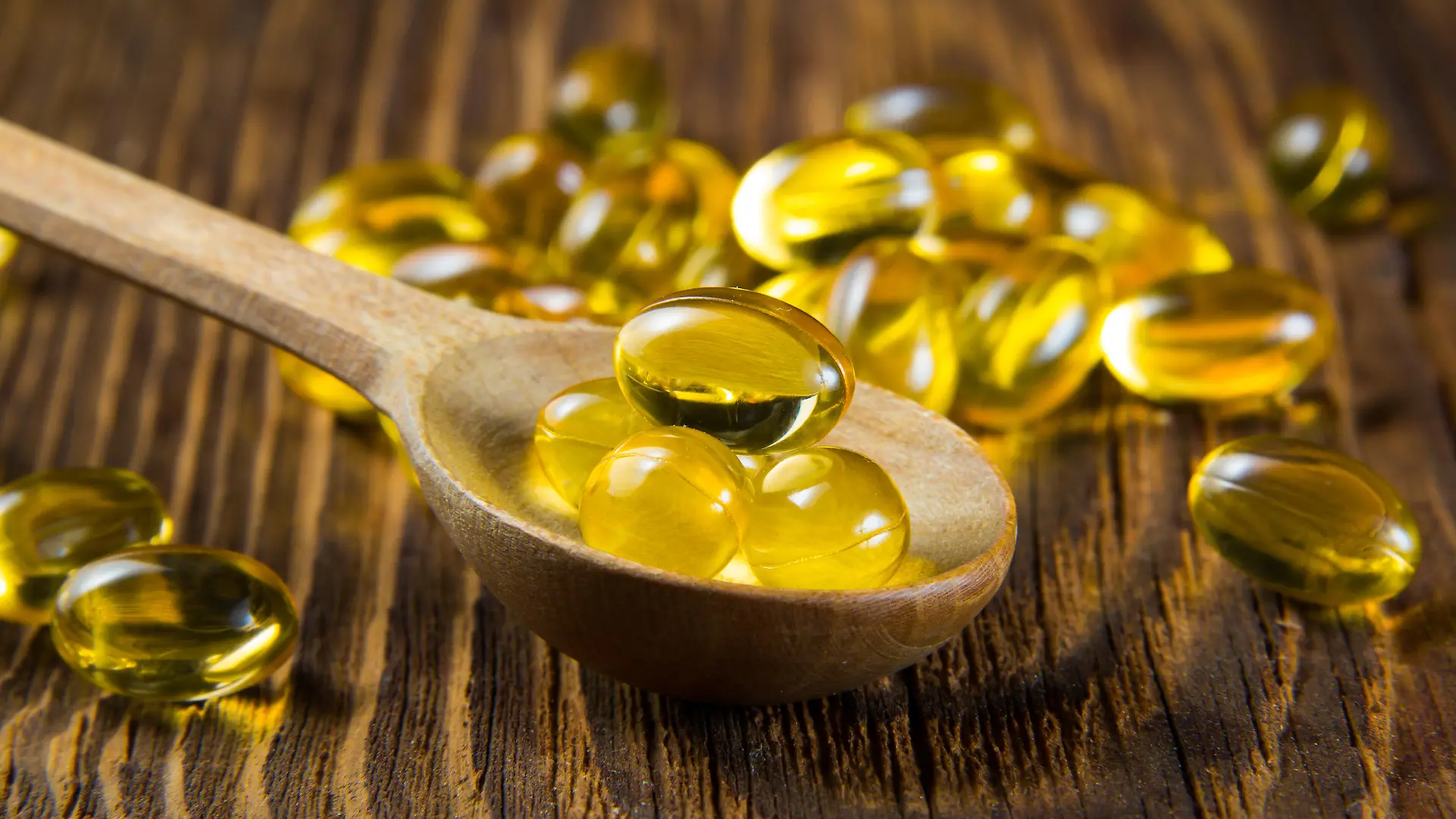 Cod-liver oil, omega3, vitamin D capsules on wooden spoon