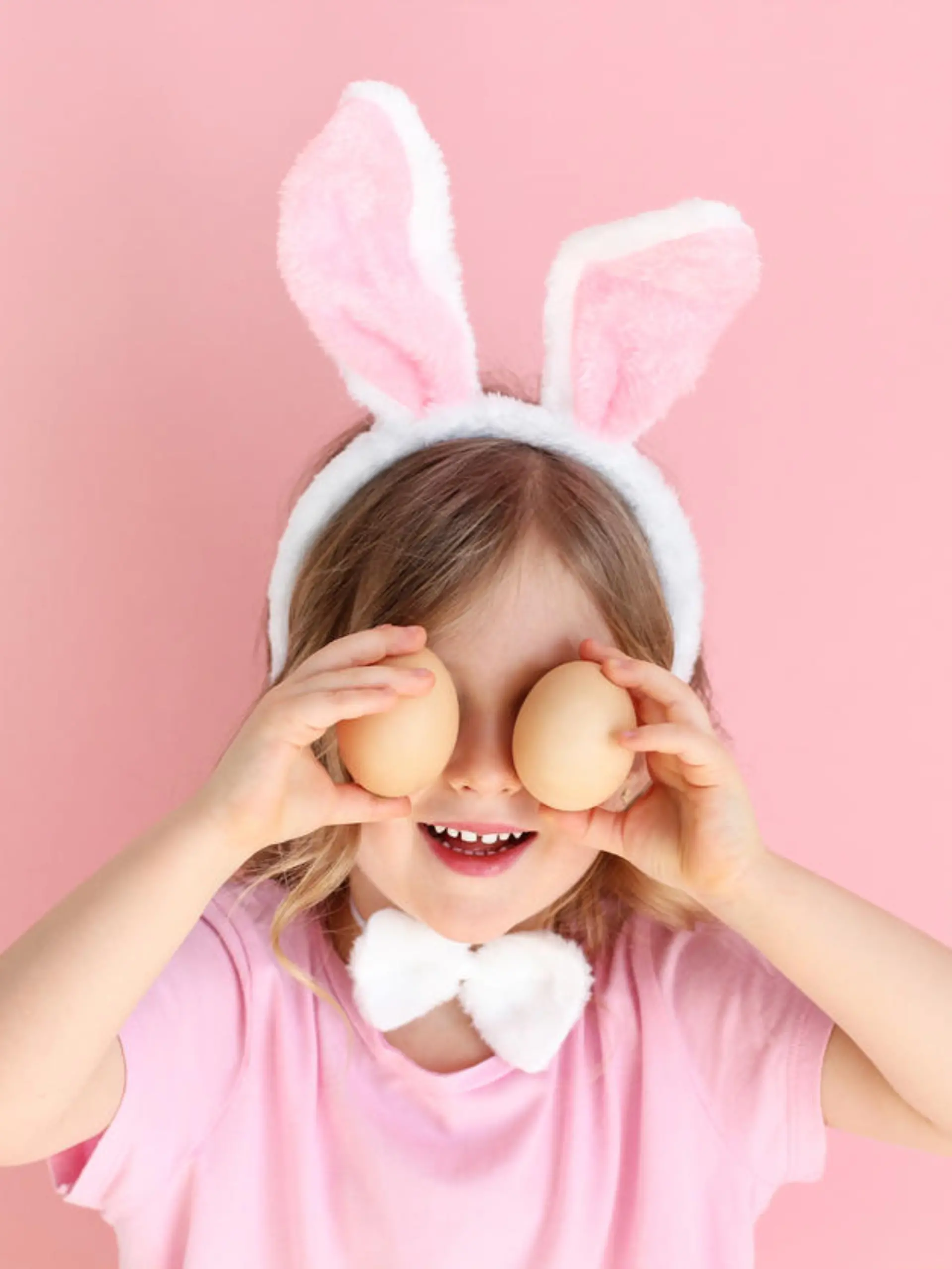 Cute little child wearing bunny ears holding egg on Easter day . Easter girl portrait, funny emotions, surprise. Copyspace for text.