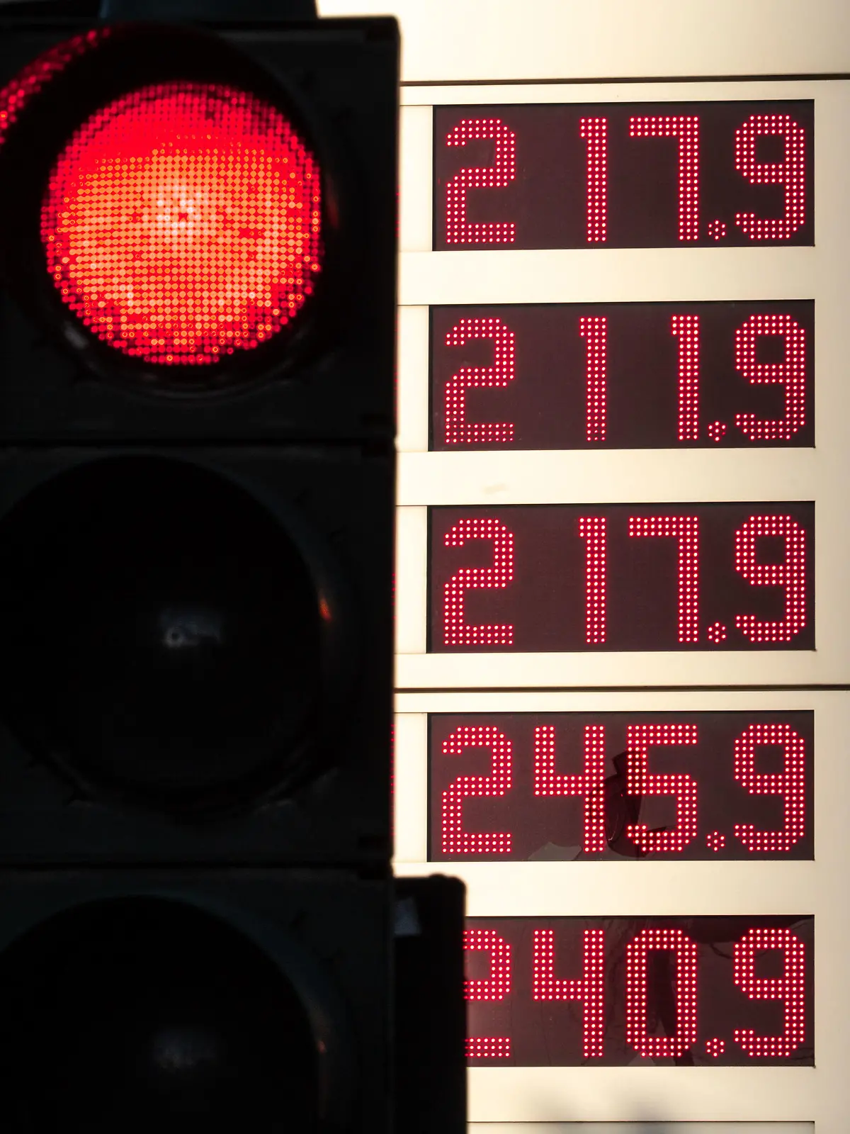 08.03.2022, Hessen, Frankfurt/Main: Die Preise für verschiedene Benzin- und Dieselsorten werden an einer Tankstelle hinter einer roten Ampel (l) angezeigt. Der Ukraine-Krieg hat die Spritpreise erstmals über die Schwelle von zwei Euro steigen lassen. Foto: Frank Rumpenhorst/dpa +++ dpa-Bildfunk +++