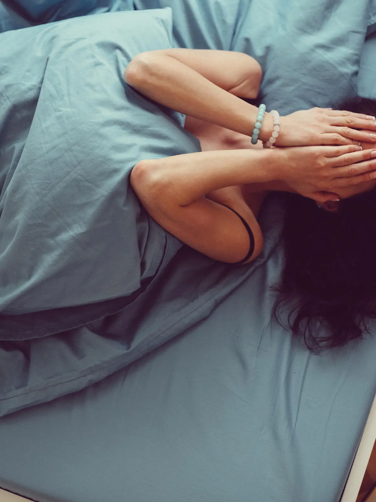 Depressed woman in bed with hands on face