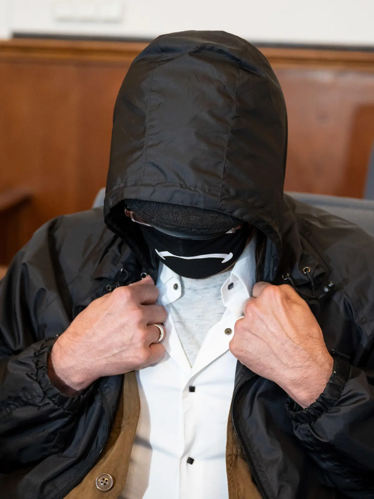 ARCHIV - 04.08.2020, Nordrhein-Westfalen, Dortmund: Der Angeklagte verbirgt auf der Anklagebank im Landgericht sein Gesicht hinter einer Gesichtsmaske, einer Brille und unter einer Kapuze. Der Mann wurde inzwischen rechtskräftig verurteilt, die damals 16-jährige Schülerin Nicole-Denise Schalla ermordet zu haben. Er hat kurz vor Vollstreckung der Haft seine Fußfessel abgelegt und ist verschwunden (zu dpa: «Verurteilter Mörder legt vor Haft Fußfessel ab - Polizei fahndet») Foto: Bernd Thissen/dpa +++ dpa-Bildfunk +++