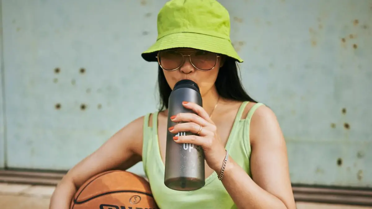 Sportliche Frau trinkt aus "air up"-Flasche.