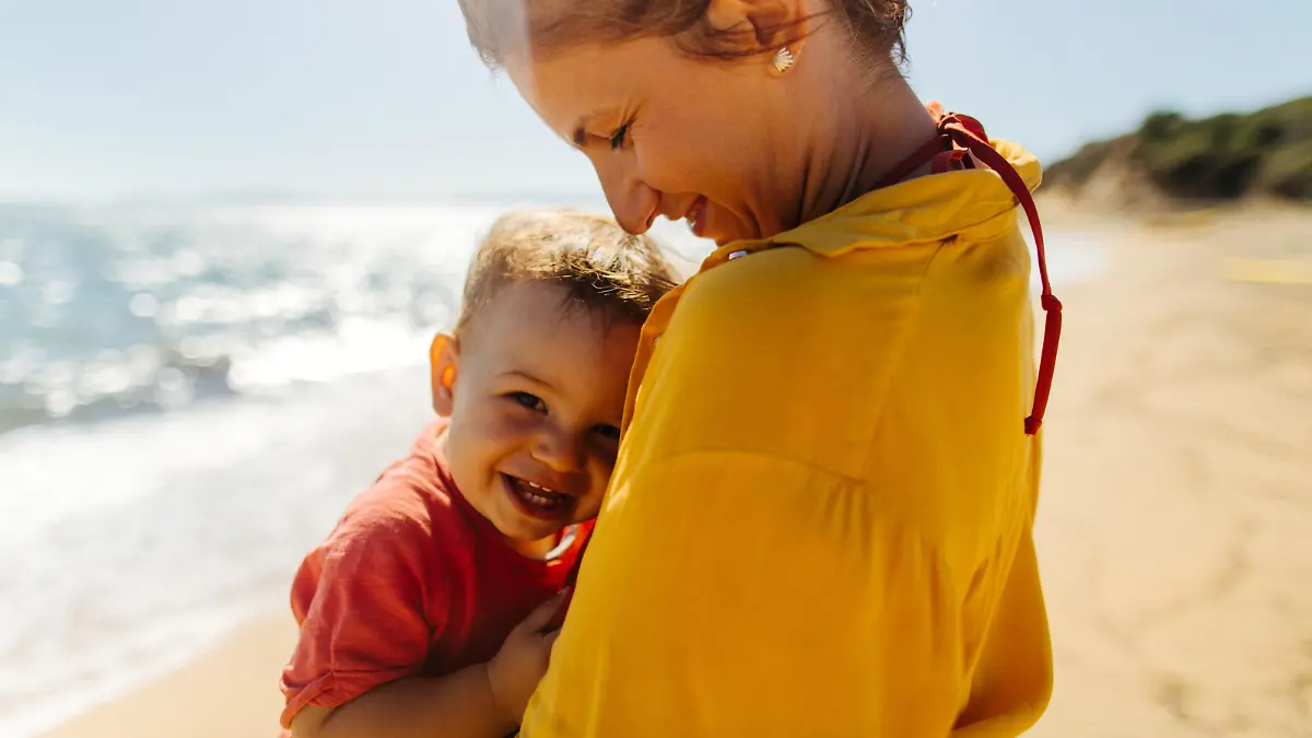 Photo of mother hugging her baby boy while enjoying together at the beach