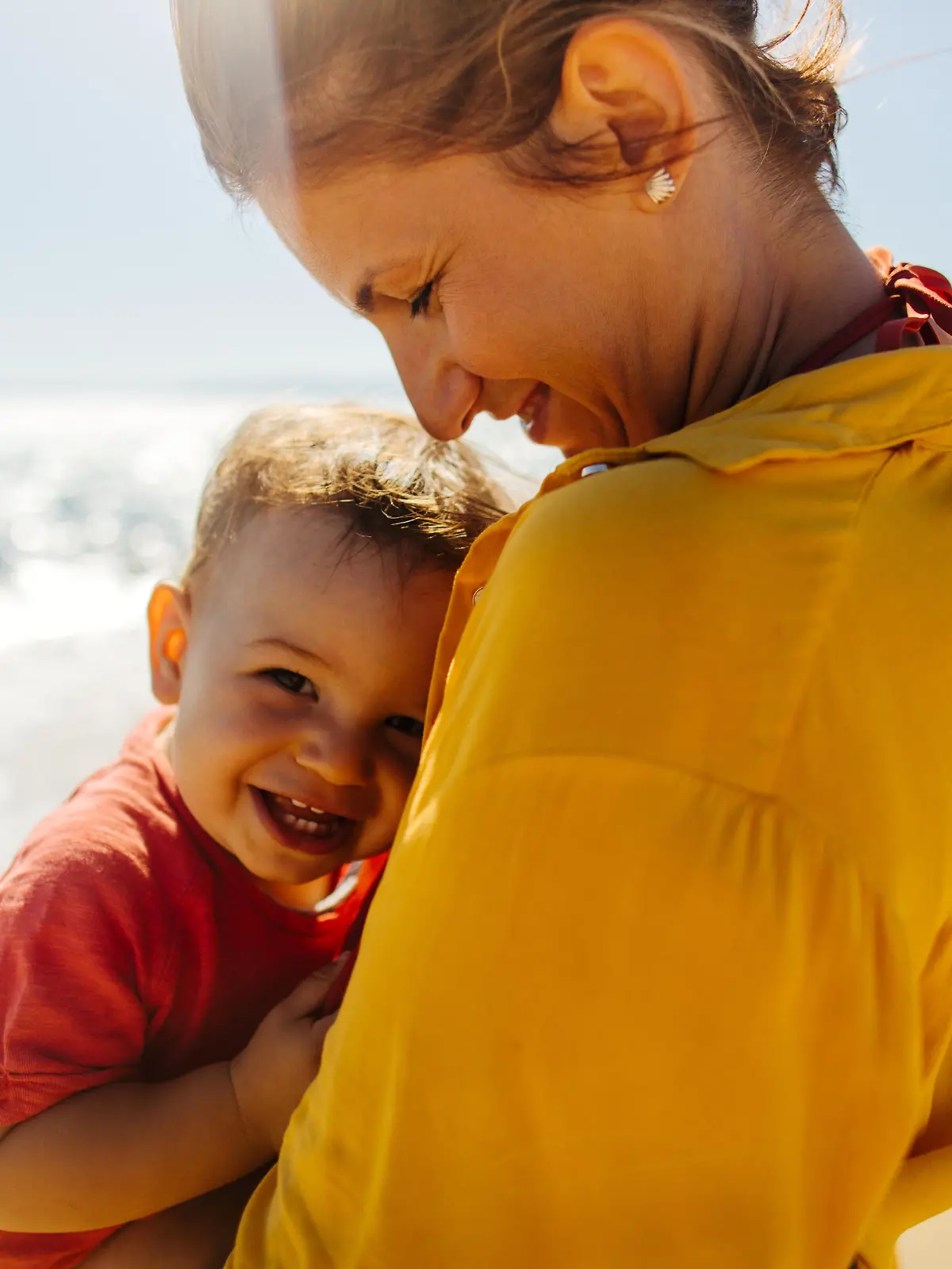 Photo of mother hugging her baby boy while enjoying together at the beach