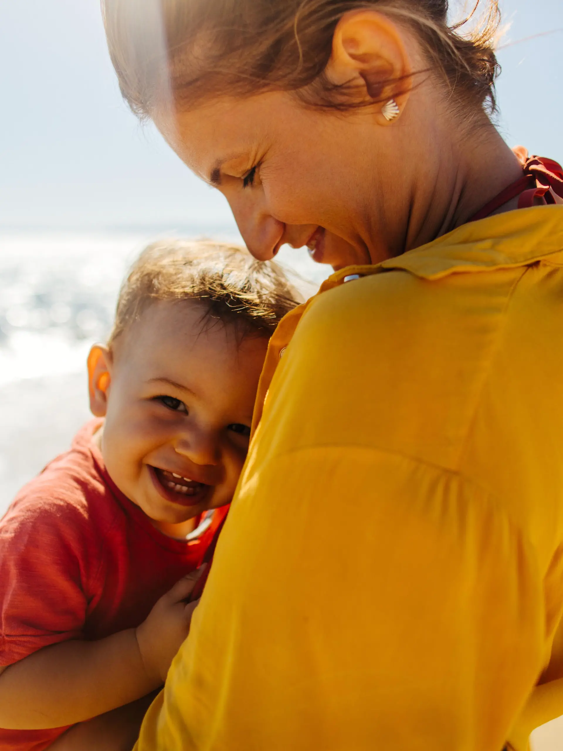 Photo of mother hugging her baby boy while enjoying together at the beach
