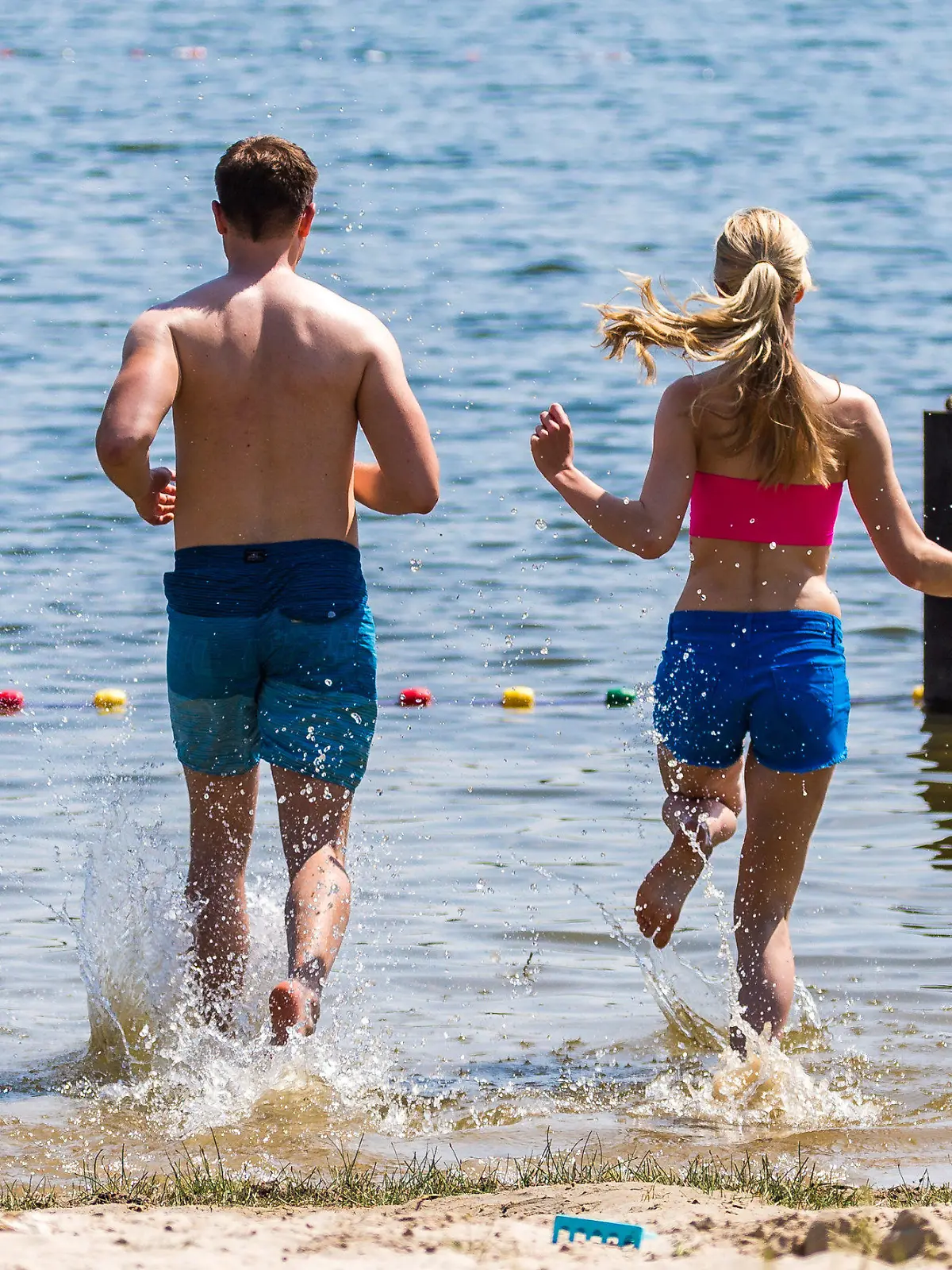 28.05.2018, Niedersachsen, Oldenburg: Eine Frau und ein Mann laufen zum Baden bei sommerlichen Temperaturen und Sonnenschein in den Woldsee. Foto: Mohssen Assanimoghaddam/dpa +++ dpa-Bildfunk +++