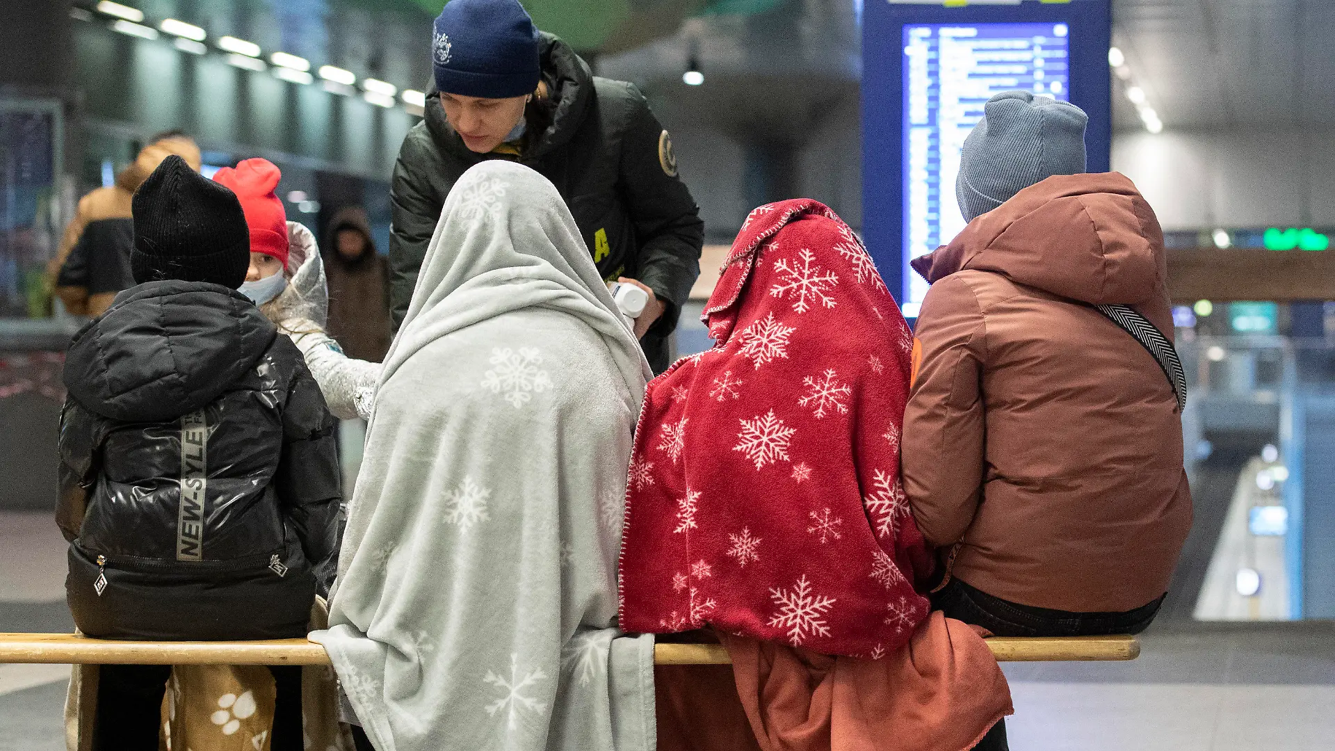06.03.2022, Berlin: In Decken gehüllt sitzen diese Kinder aus dem ukrainischen Kriegsgebiet im Berliner Hauptbahnhof, während sich ein ehrenamtlicher Helfer um die Kinder kümmert. Auch an diesem Morgen sind bereits zahlreiche Flüchtlinge aus dem Kriegsgebiet in Berlin angekommen. Russische Truppen marschierten am 24. Februar in die Ukraine ein. Foto: Paul Zinken/dpa +++ dpa-Bildfunk +++