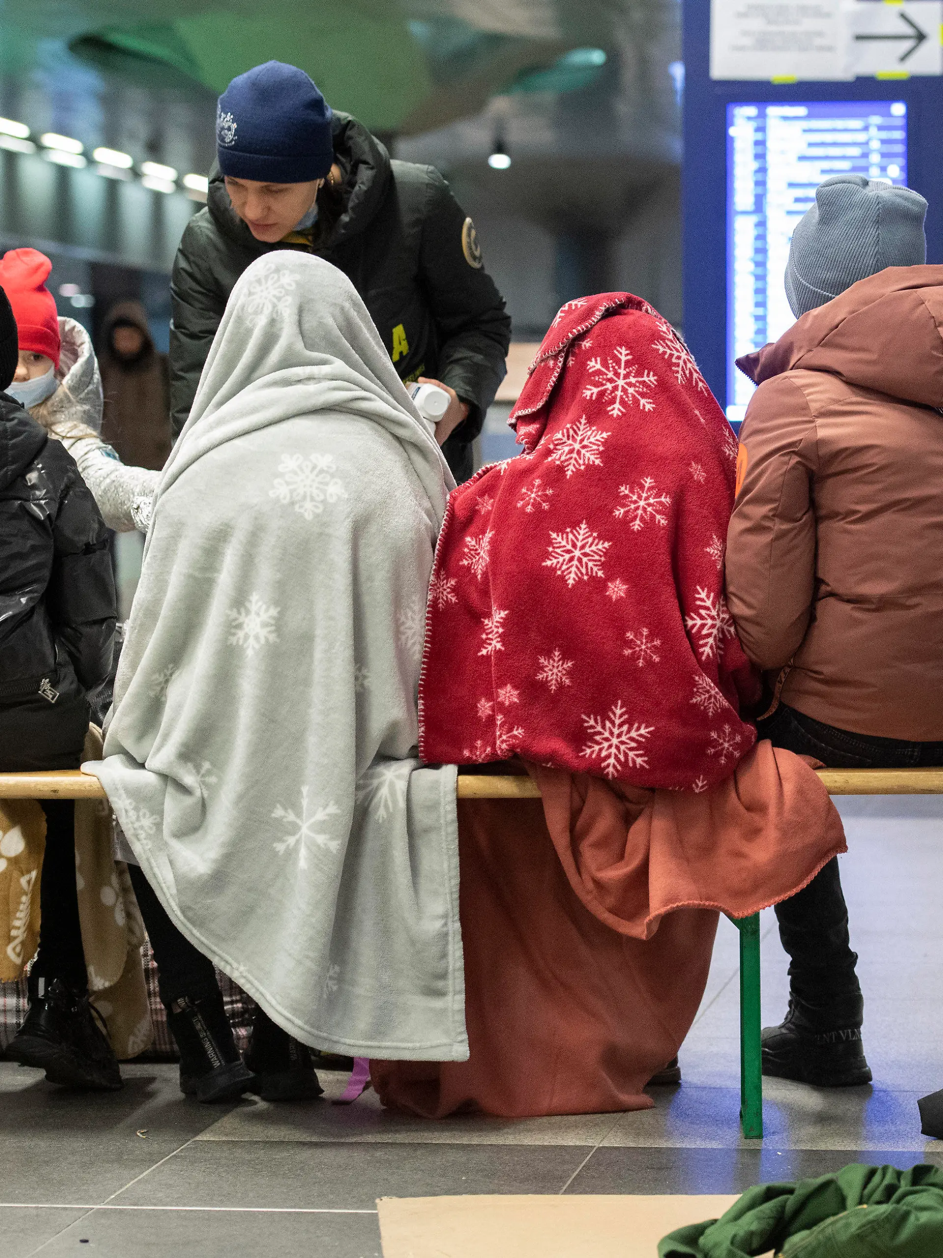 06.03.2022, Berlin: In Decken gehüllt sitzen diese Kinder aus dem ukrainischen Kriegsgebiet im Berliner Hauptbahnhof, während sich ein ehrenamtlicher Helfer um die Kinder kümmert. Auch an diesem Morgen sind bereits zahlreiche Flüchtlinge aus dem Kriegsgebiet in Berlin angekommen. Russische Truppen marschierten am 24. Februar in die Ukraine ein. Foto: Paul Zinken/dpa +++ dpa-Bildfunk +++