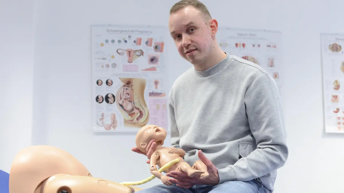 PRODUKTION - 23.02.2022, Nordrhein-Westfalen, Bielefeld: Jonas Küppers, männliche Hebamme, hält eine Neugeborenen-Übungspuppe mit Nabelschnur. Küppers absolviert ein duales Studium, um den Beruf der Hebamme zu lernen. In Deutschland sind Männer im Hebammen-Beruf extrem selten. (zu dpa: «Als Mann im Frauen-Beruf Hebamme - im Kreißsaal eine extreme Ausnahme») Foto: Friso Gentsch/dpa +++ dpa-Bildfunk +++