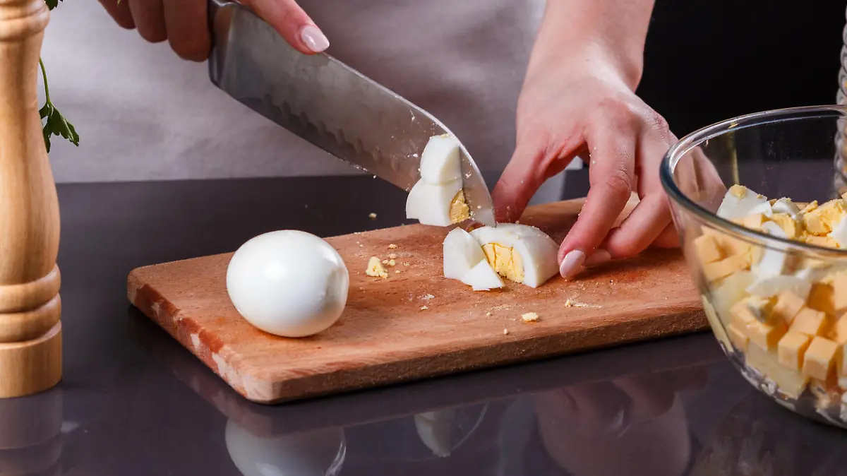 young woman in a gray apron cuts a boiled egg.