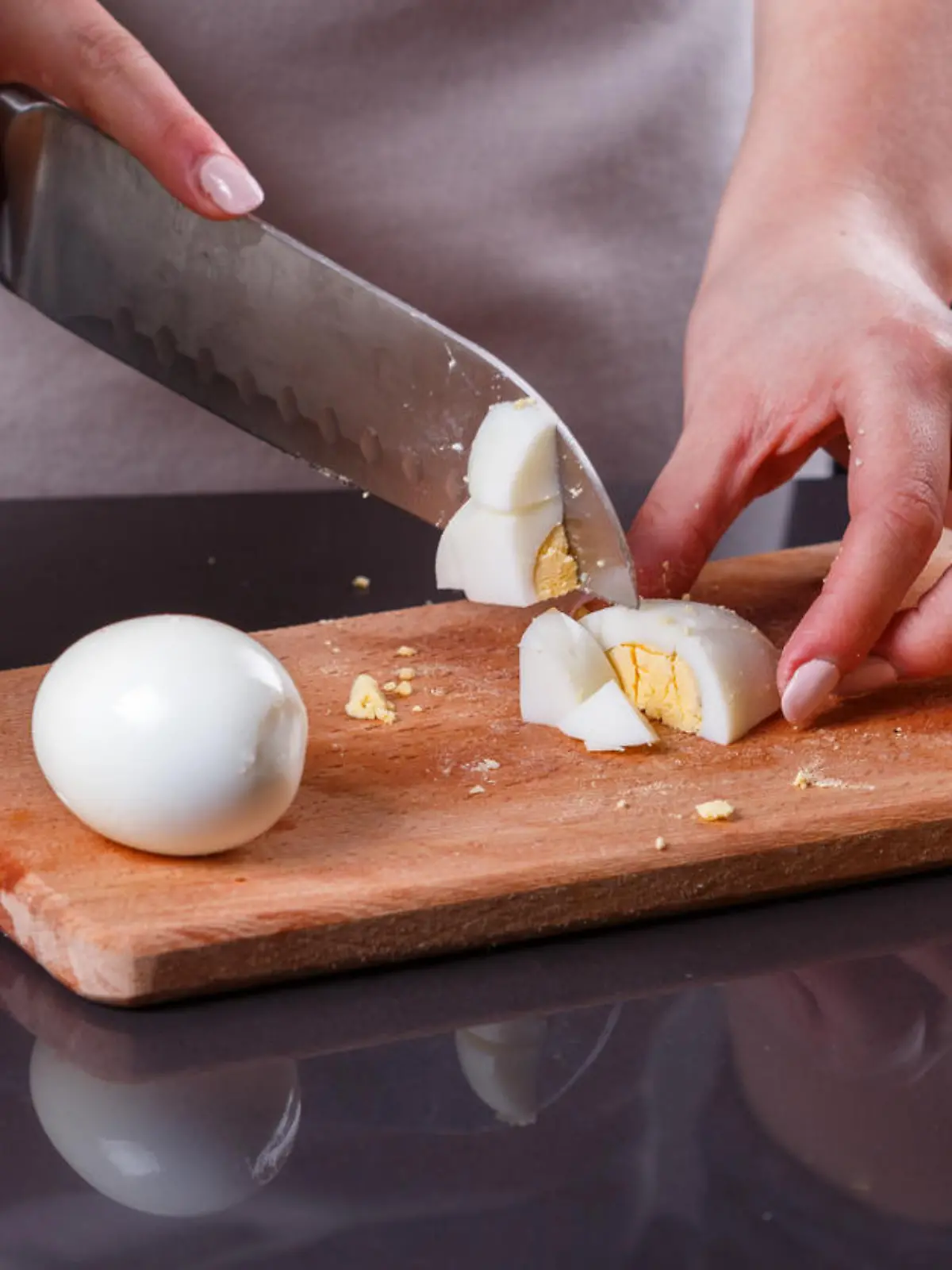 young woman in a gray apron cuts a boiled egg.