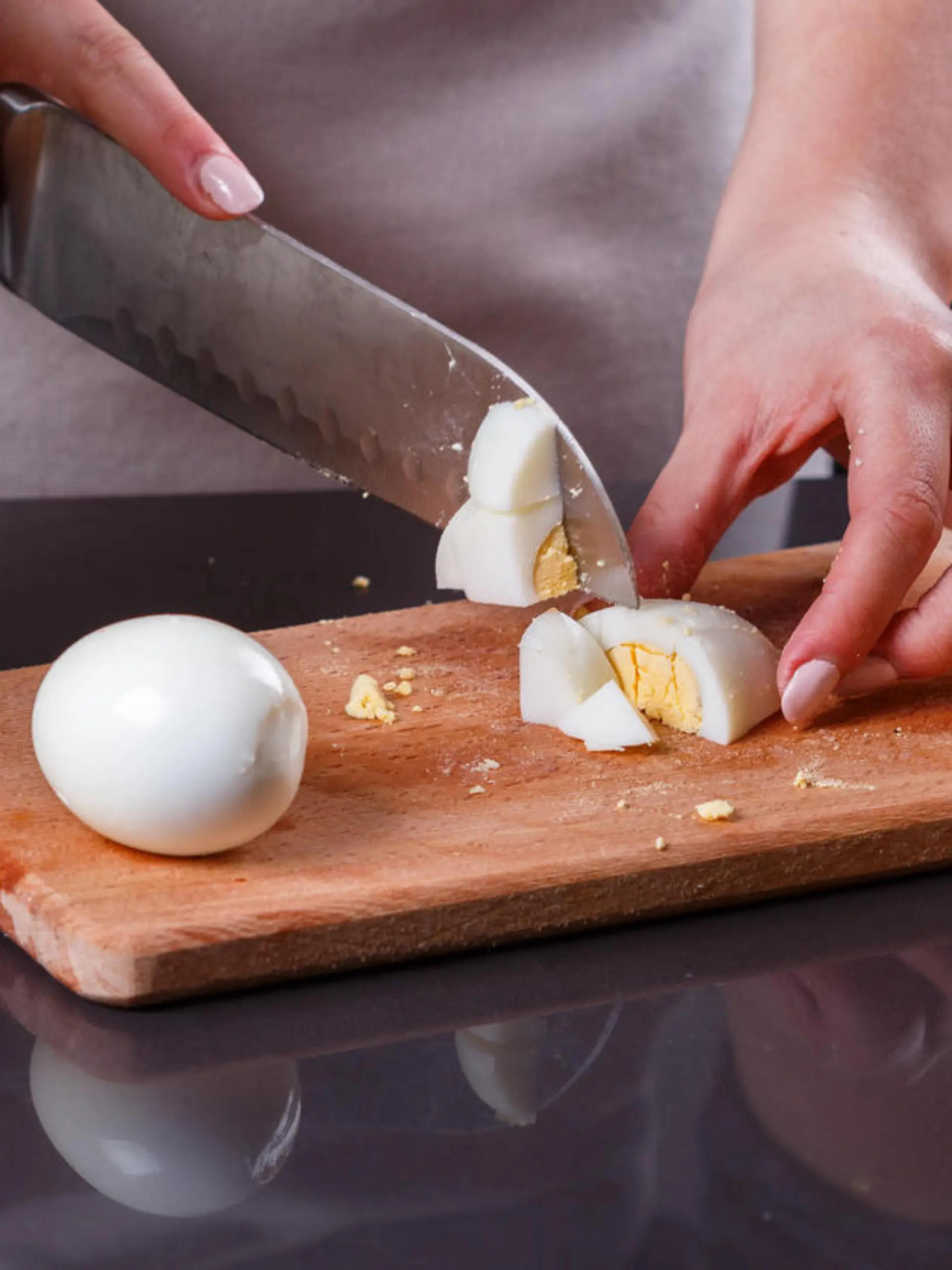 young woman in a gray apron cuts a boiled egg.